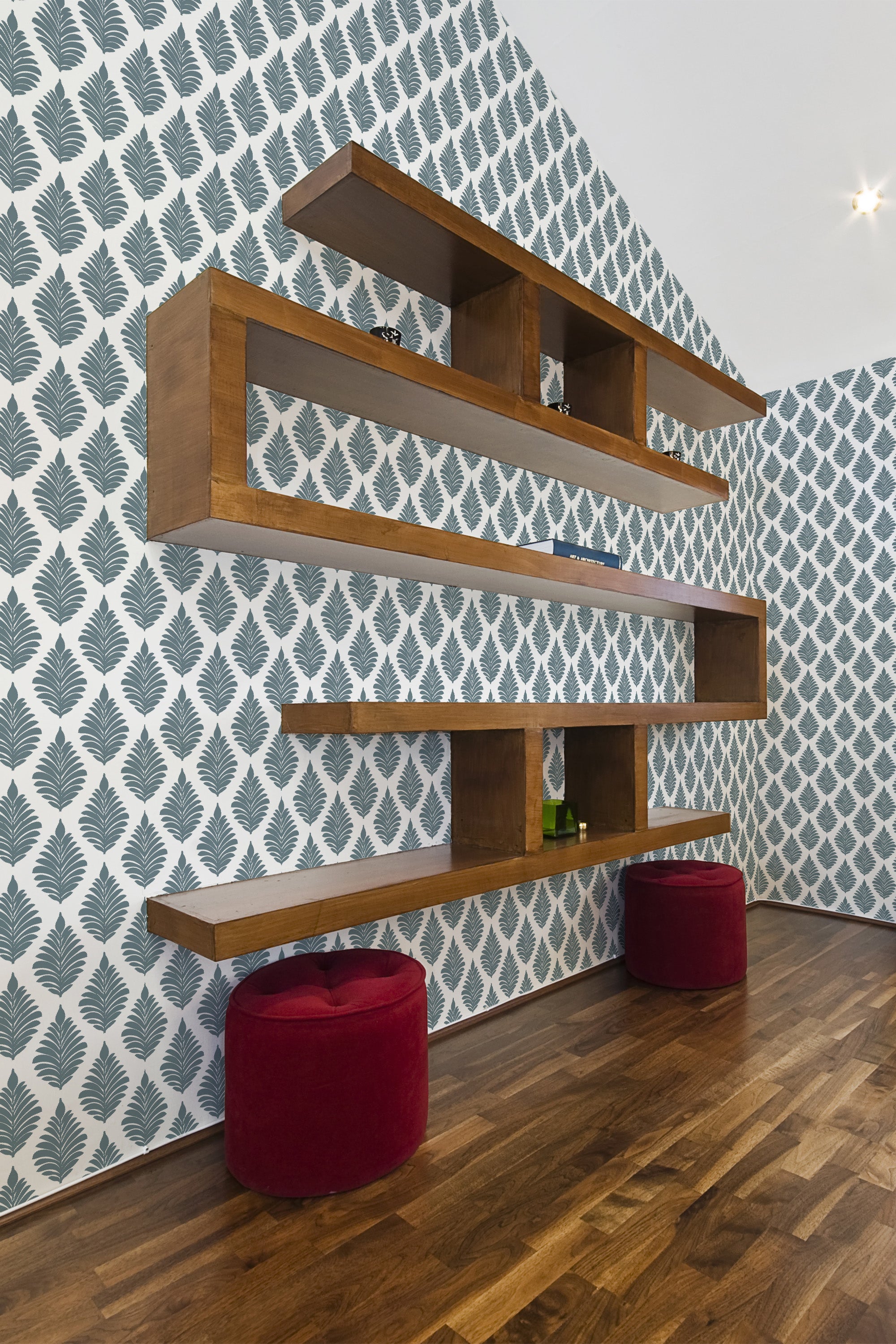 Room with wallpaper adorned in a French leaf pattern in a repeating motif of dark green leaves on a white background. The wooden floors and shelves complement the classic design, creating an elegant and cohesive look with traditional wallpaper.