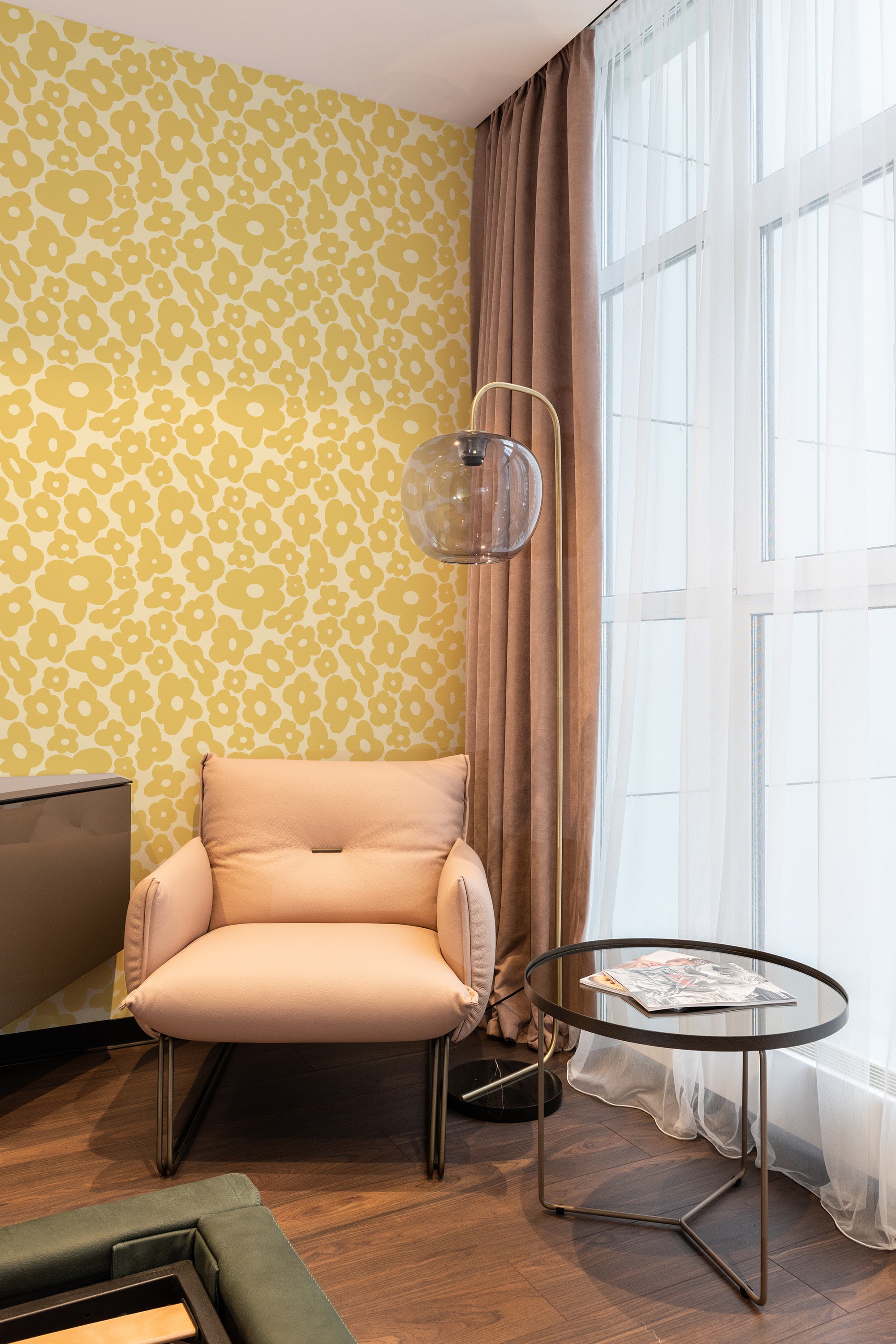 An image of a room with yellow wallpaper covered in a repeating pattern of funky, abstract flowers in white. The floral design contrasts with the modern decor, lending a vibrant and playful touch to the space. Traditional wallpaper.