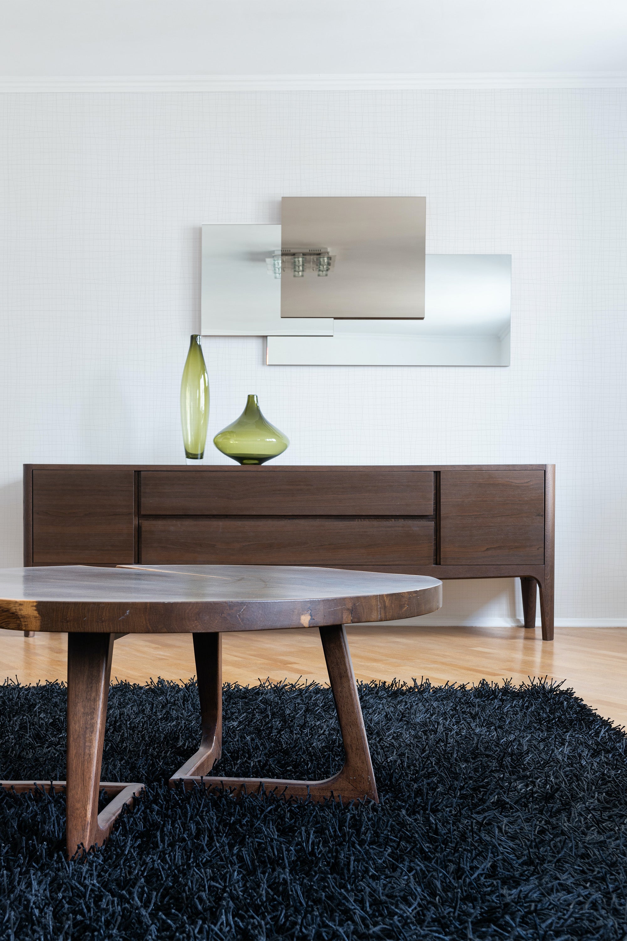 A soft, textured wallpaper in a subtle linen pattern adds an understated elegance to the room, blending seamlessly with modern wooden furniture and minimalistic decor elements, offering a refined touch typical of traditional wallpaper.