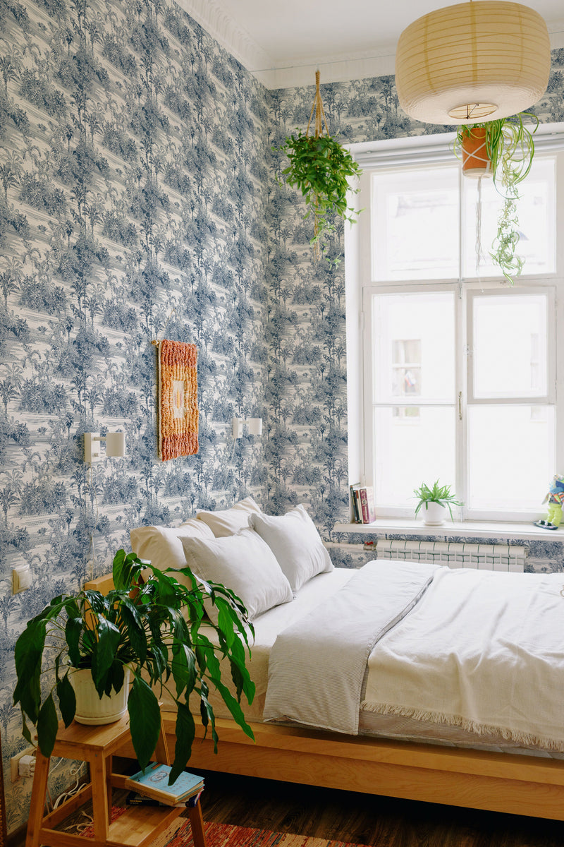 A bedroom with walls covered in a jungle-themed design in shades of blue and white, illustrating dense foliage, trees, and wildlife. The natural scenery extends from ceiling to floor. Traditional wallpaper.