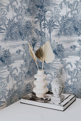 Self-adhesive wallpaper with a jungle-themed design in muted blue tones, displaying detailed palm trees, tropical foliage, and animals on a cream background.