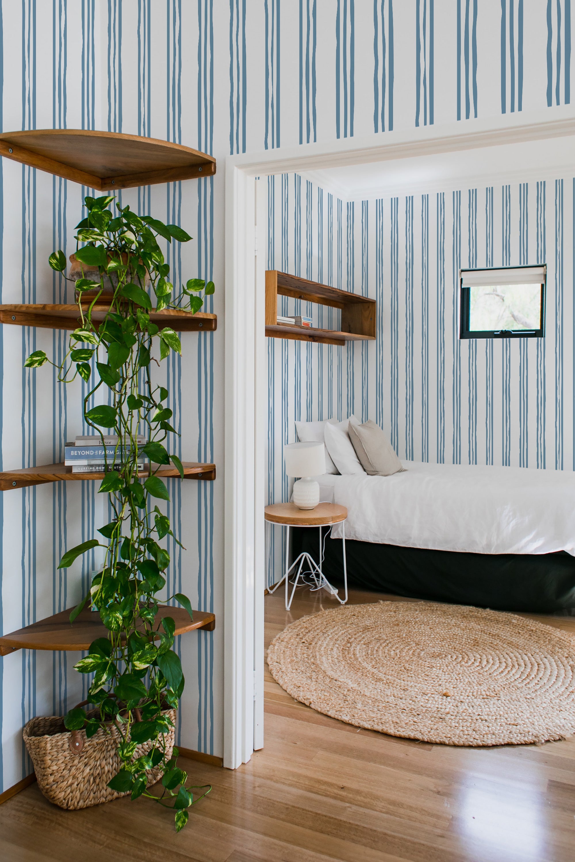 Blue striped wallpaper with vertical lines in varying thicknesses, creating a classic, balanced pattern in a room with wooden floors and minimal decor,raditional wallpaper.