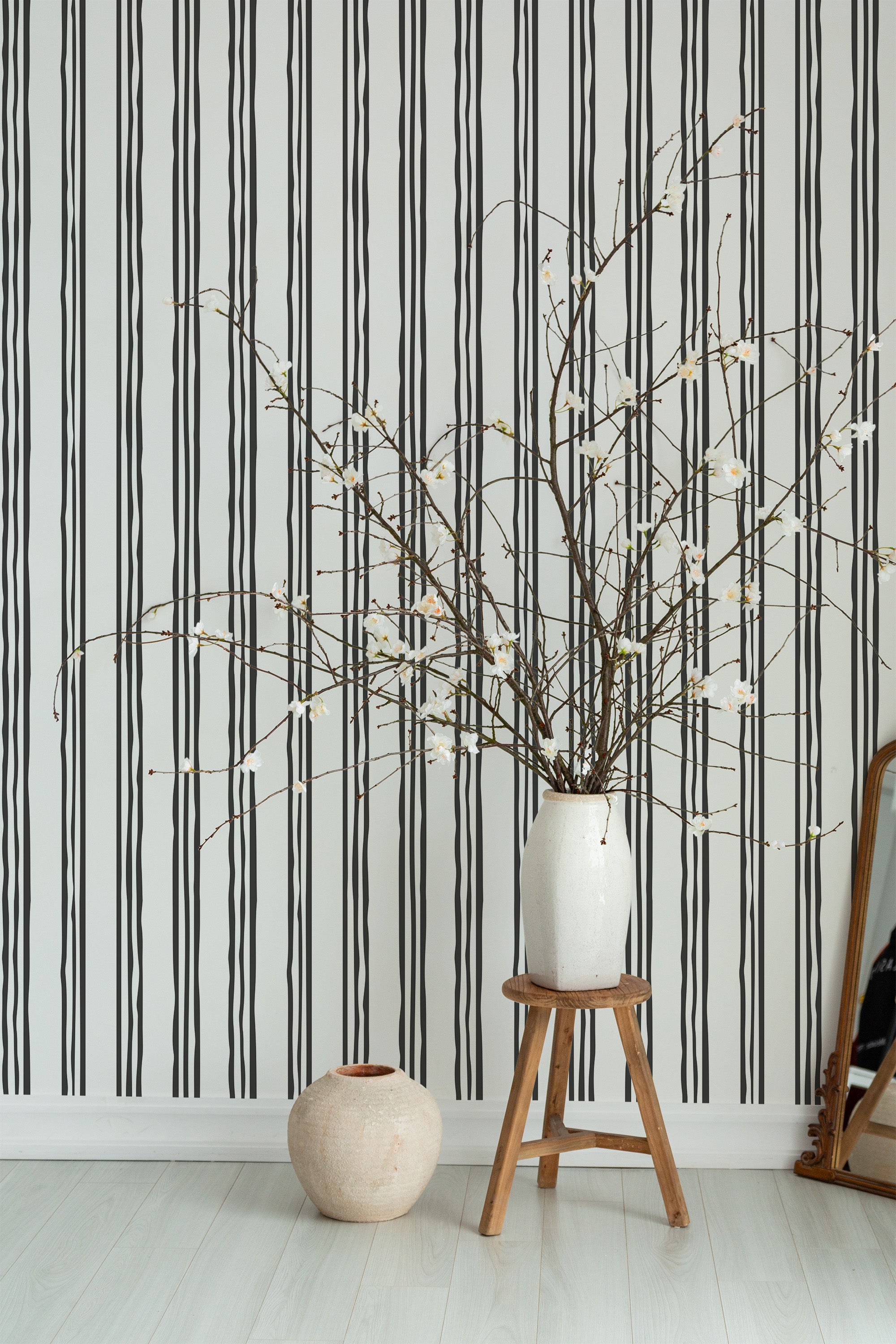 Self-adhesive wallpaper with a bold striped pattern in alternating black, gray, and white vertical lines, creating a striking and modern backdrop for the room.