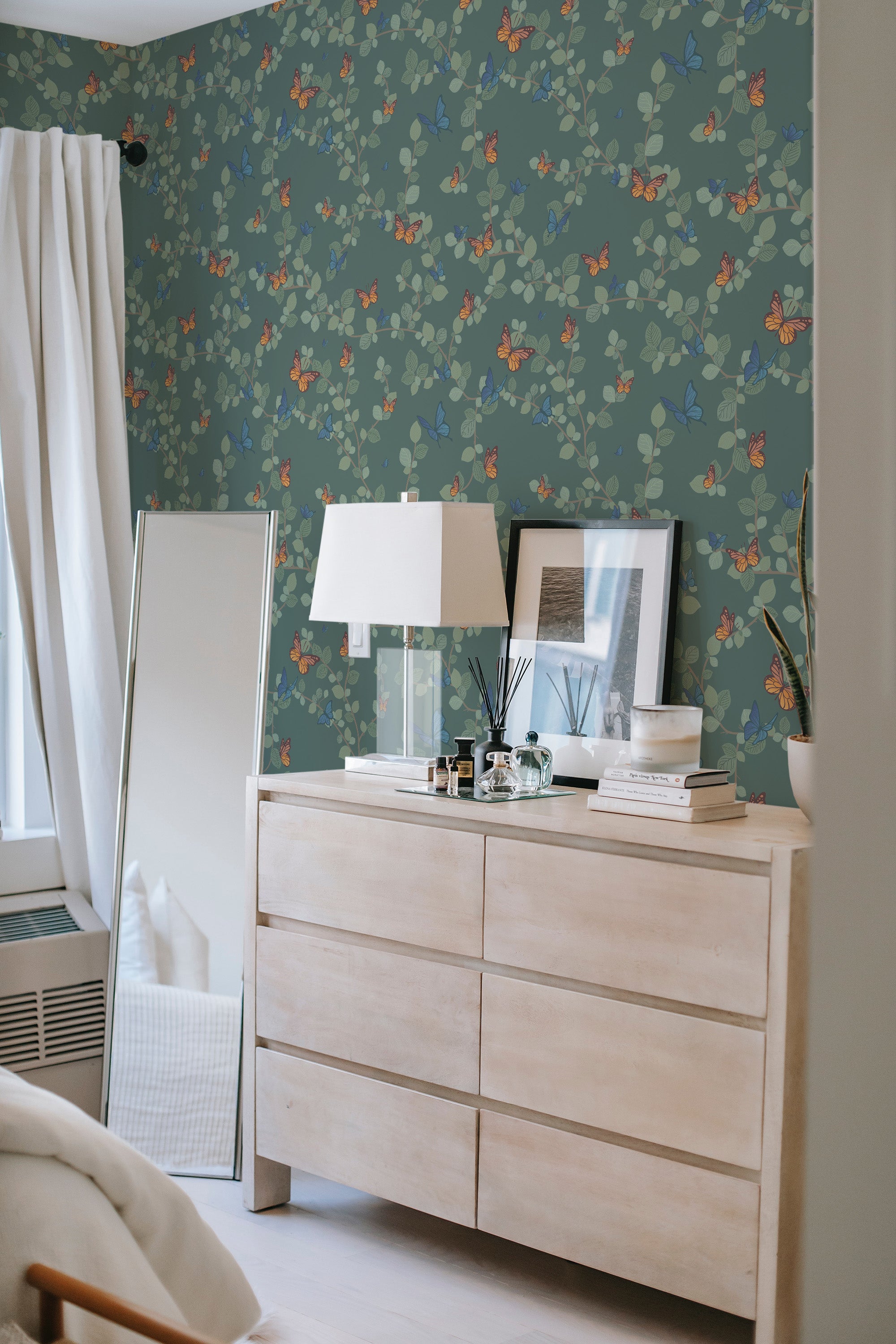 Wallpaper with a whimsical butterfly design on a muted teal background, adorned with colorful butterflies scattered among delicate green leaves, creating a lively yet elegant vibe. Traditional wallpaper.