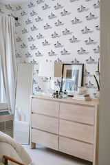 The wallpaper design in the room includes black paper ships floating on a white background, creating a minimalist nautical theme. Traditional wallpaper.