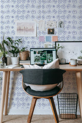 Self-adhesive wallpaper with a minimalist flower design in soft blue hues, creating a light and airy ambiance, complementing the modern workspace setup with a wooden desk and various decor items.