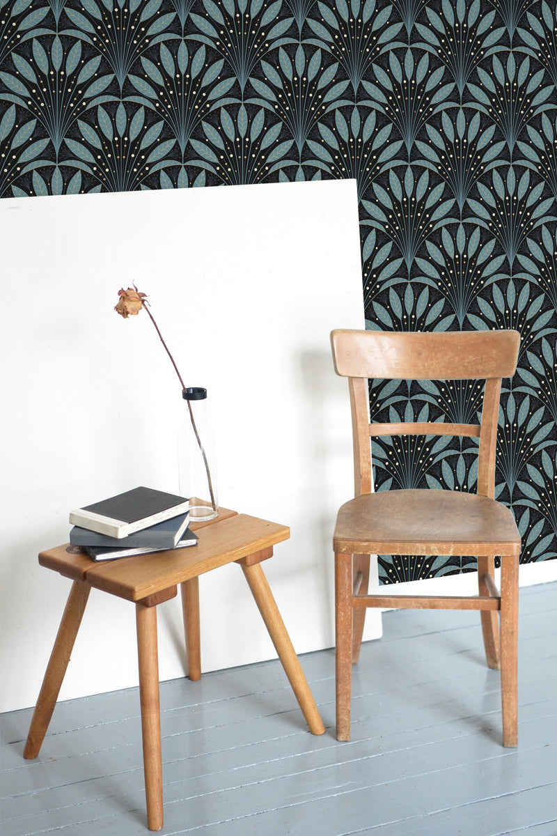 Self-adhesive wallpaper with an Art Deco-inspired pattern consisting of fan shapes in shades of black and gray, complemented by subtle gold accents. The background is dark, adding depth and contrast to the design.