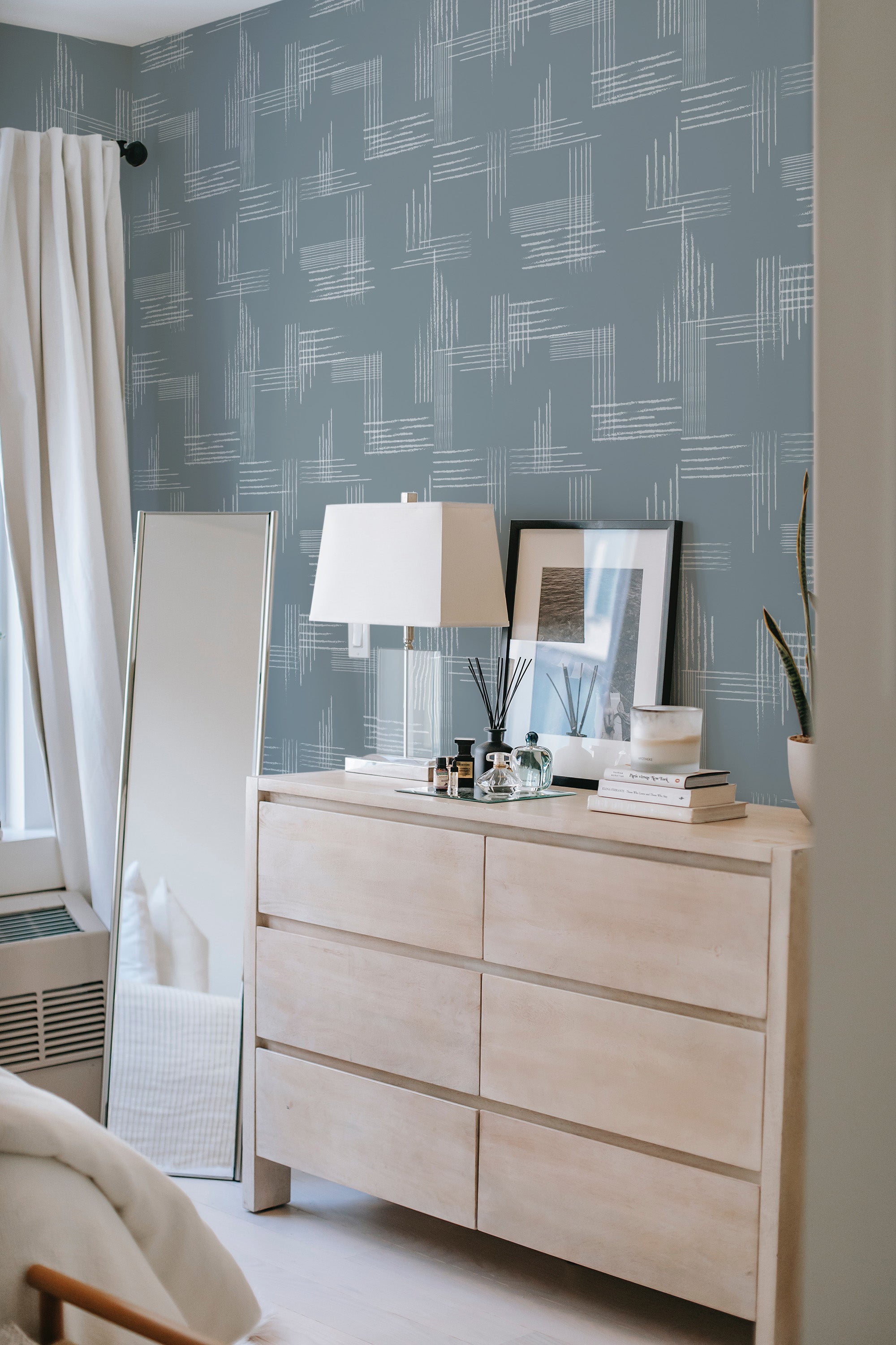 A room with blue walls adorned with a Minimalist brush tile design in white, creating a subtle yet modern abstract pattern. The geometric brush strokes give a textured look, adding depth and interest to the traditional wallpaper.