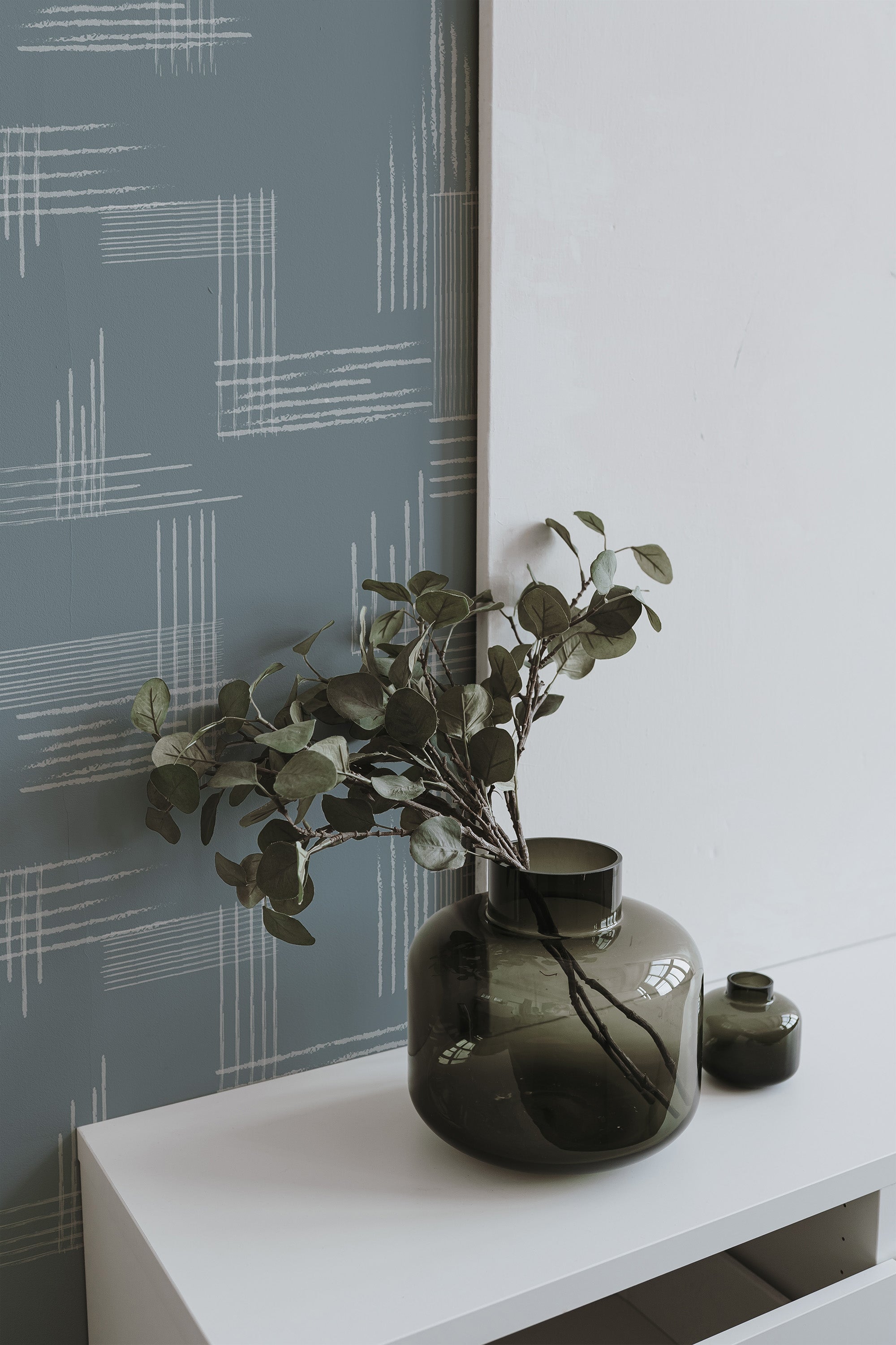 Self-adhesive wallpaper with a Minimalist brush tile design, featuring subtle, crisscrossing white lines on a muted blue-gray background.