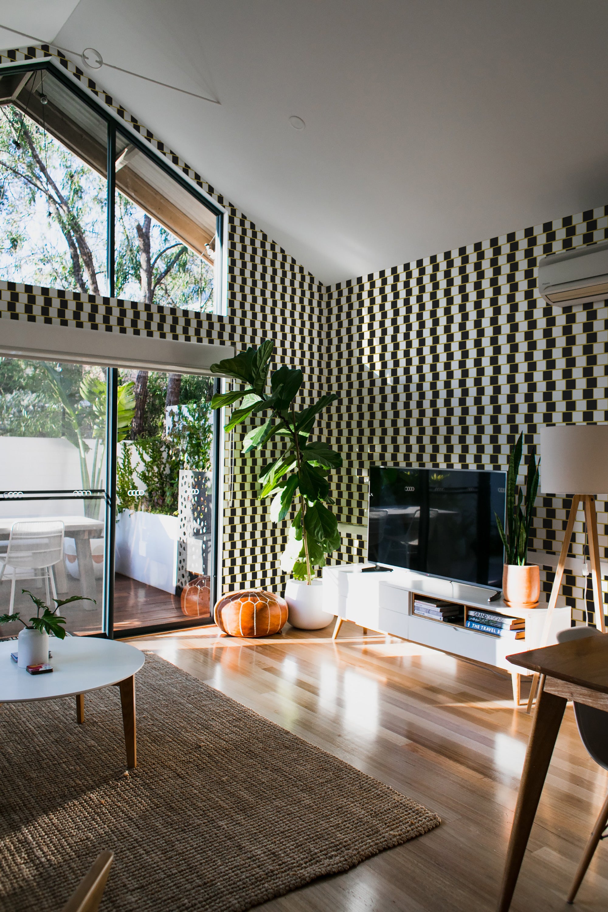 A modern living room with walls covered in geometric optical tile wallpaper, featuring a repetitive black-and-white square pattern that creates a visually striking effect. The design resembles a 3D illusion, adding depth and texture to the space, giving it a contemporary yet traditional wallpaper.