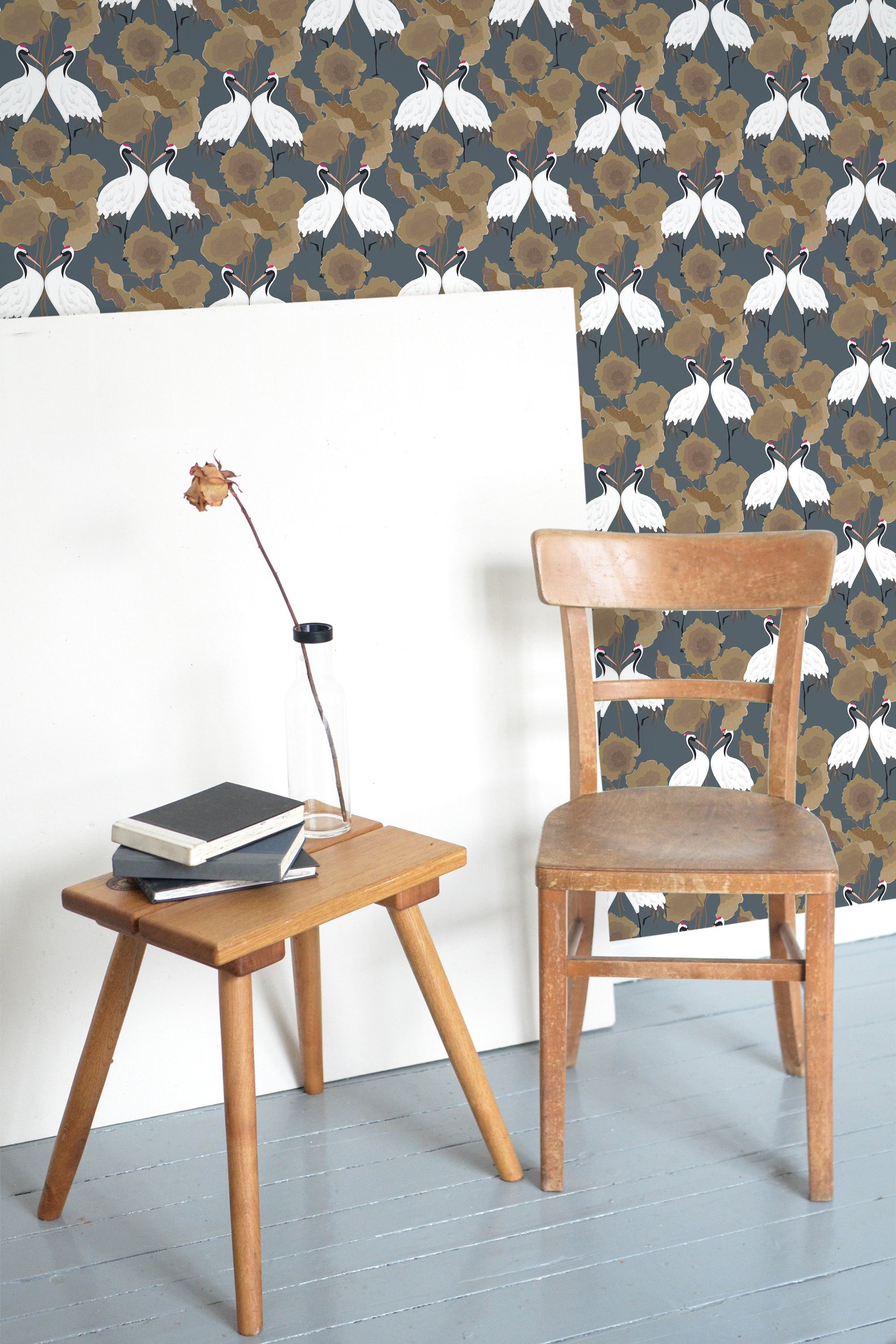 Self-adhesive wallpaper with a 'Bold Heron' design showing elegant white herons among large, brown and tan abstract foliage, set against a dark, muted background.