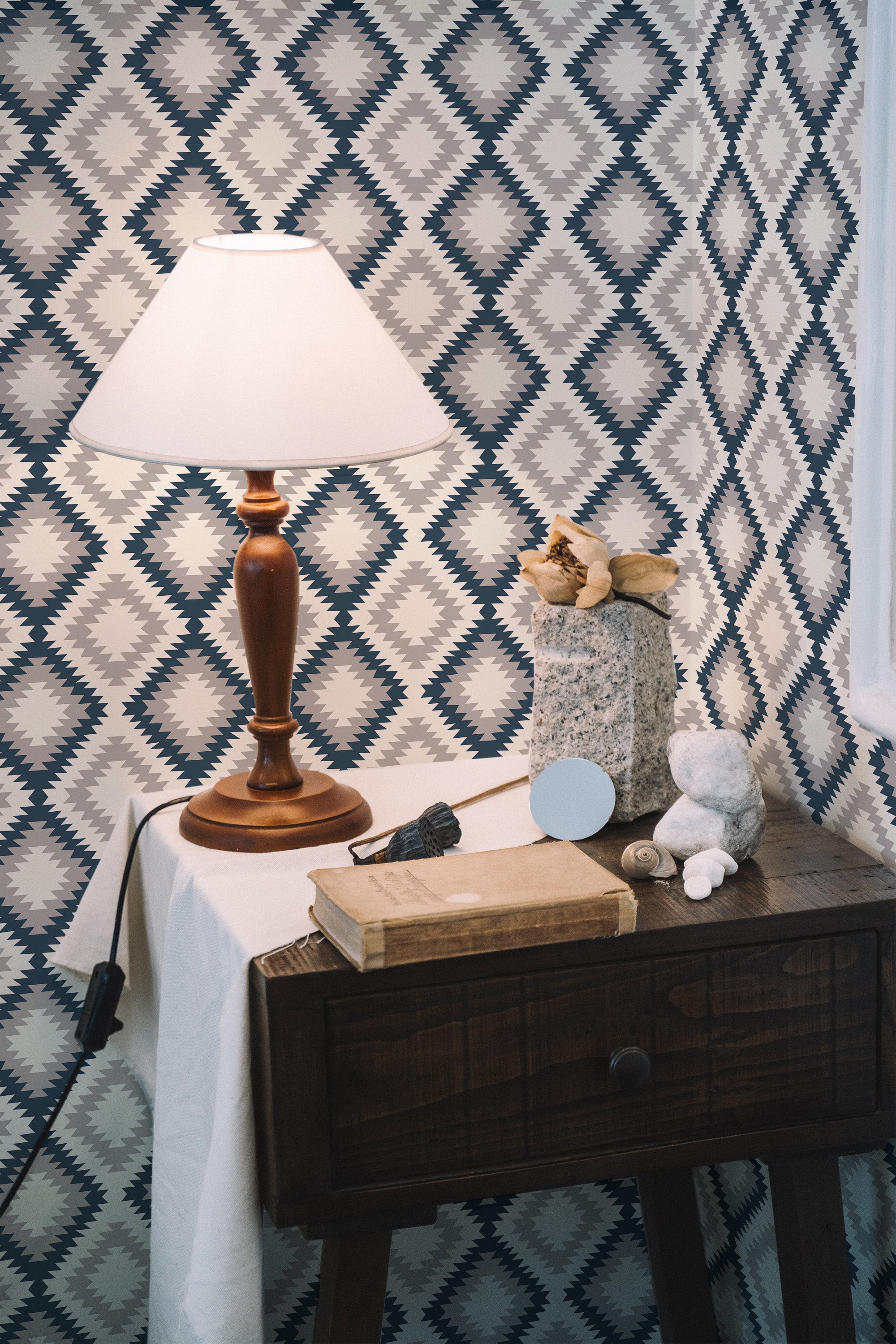 Self-adhesive Aztec geometric wallpaper with bold diamond shapes in alternating shades of blue, gray, and white creating a striking, repetitive pattern in a room with wooden furniture and soft lighting.