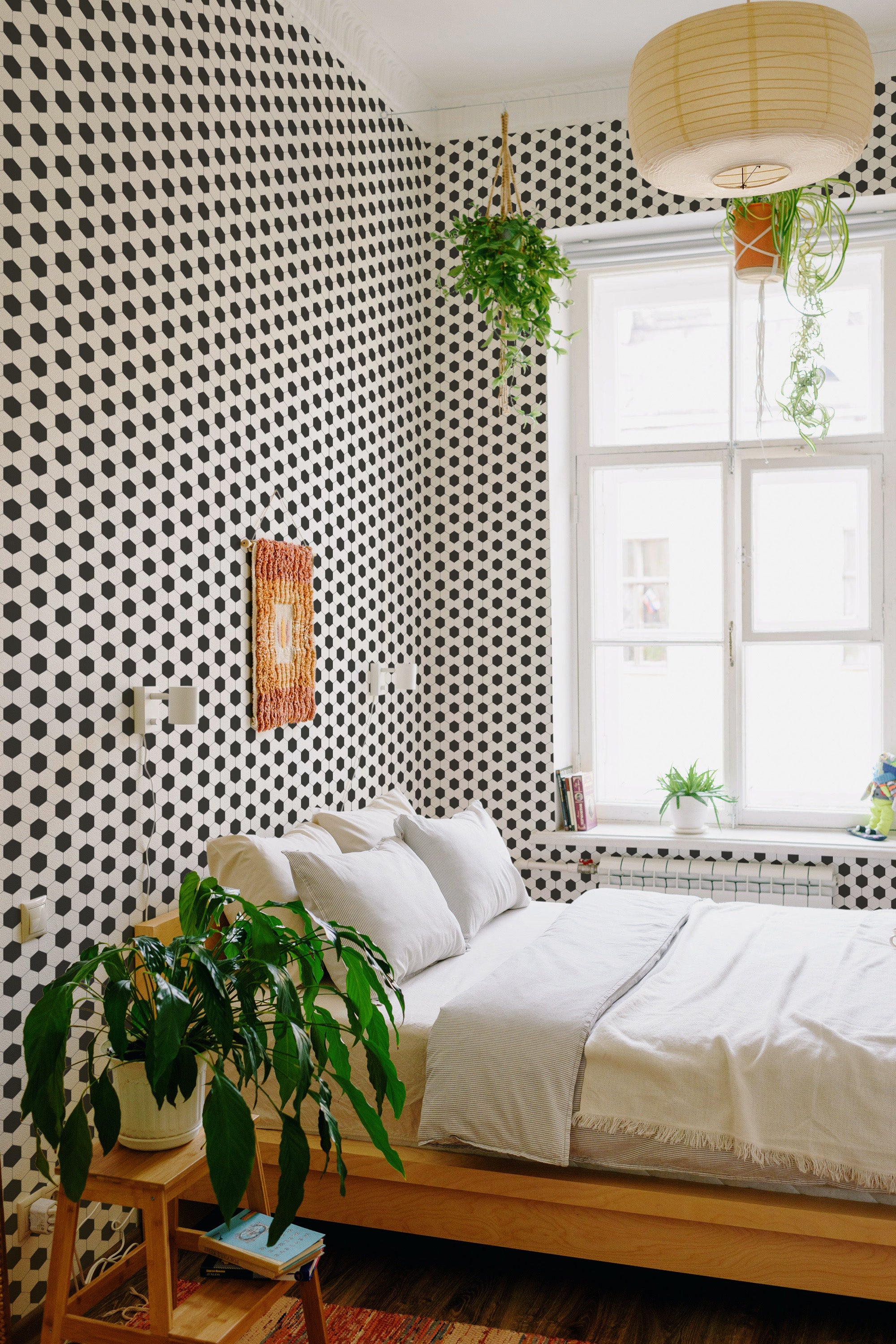 The wallpaper has a black and white hexagonal pattern, resembling football tiles, creating a bold, geometric visual effect against the wall, complementing the minimalist bedroom decor. Traditional wallpaper.