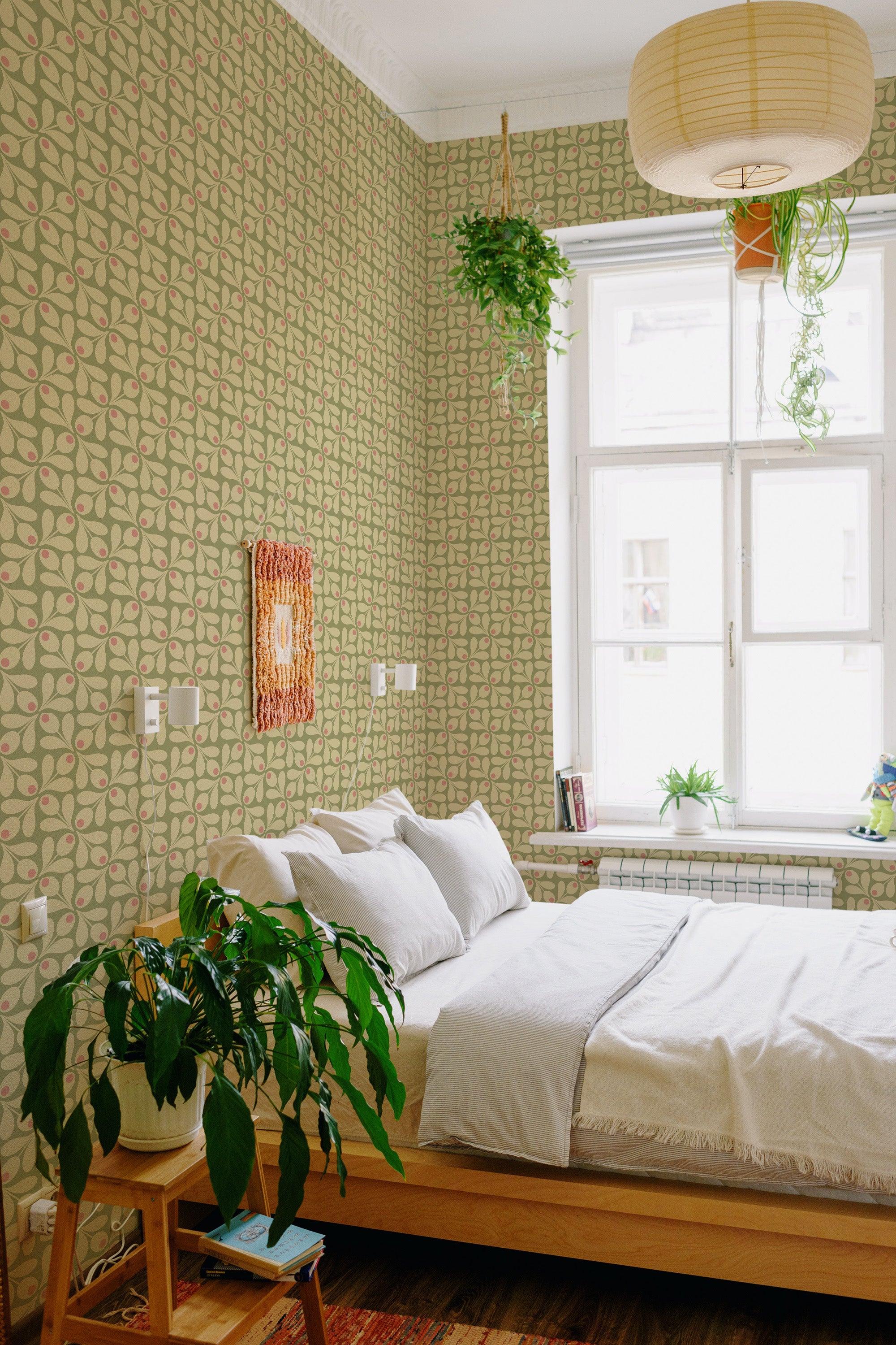 A room with green wallpaper with a floral retro pattern from the 60s, featuring repeating teardrop shapes in a muted color palette, creating a nostalgic atmosphere that complements the cozy d��cor. Traditional wallpaper.