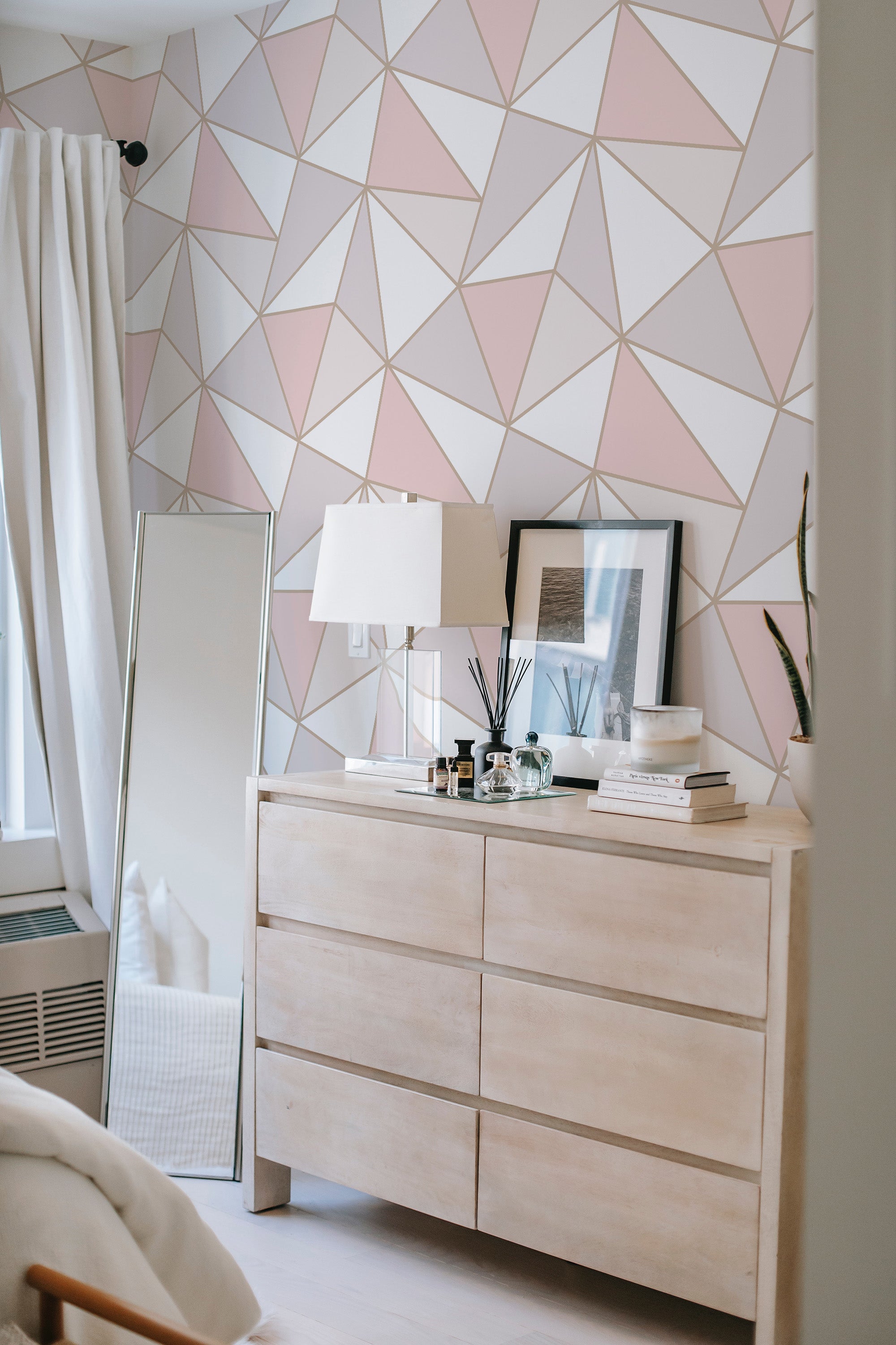 Geometric patterned wallpaper with soft pink, grey, and white triangular shapes forming a modern, yet traditional wallpaper.