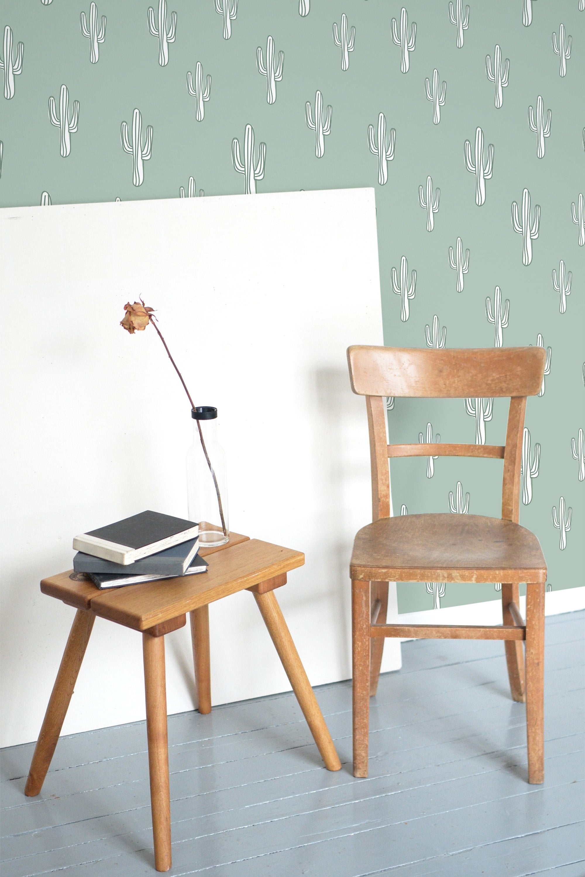 Self-adhesive wallpaper with a design of white cactus silhouettes spread evenly across a muted green background, creating a fresh, minimalist look in the room.