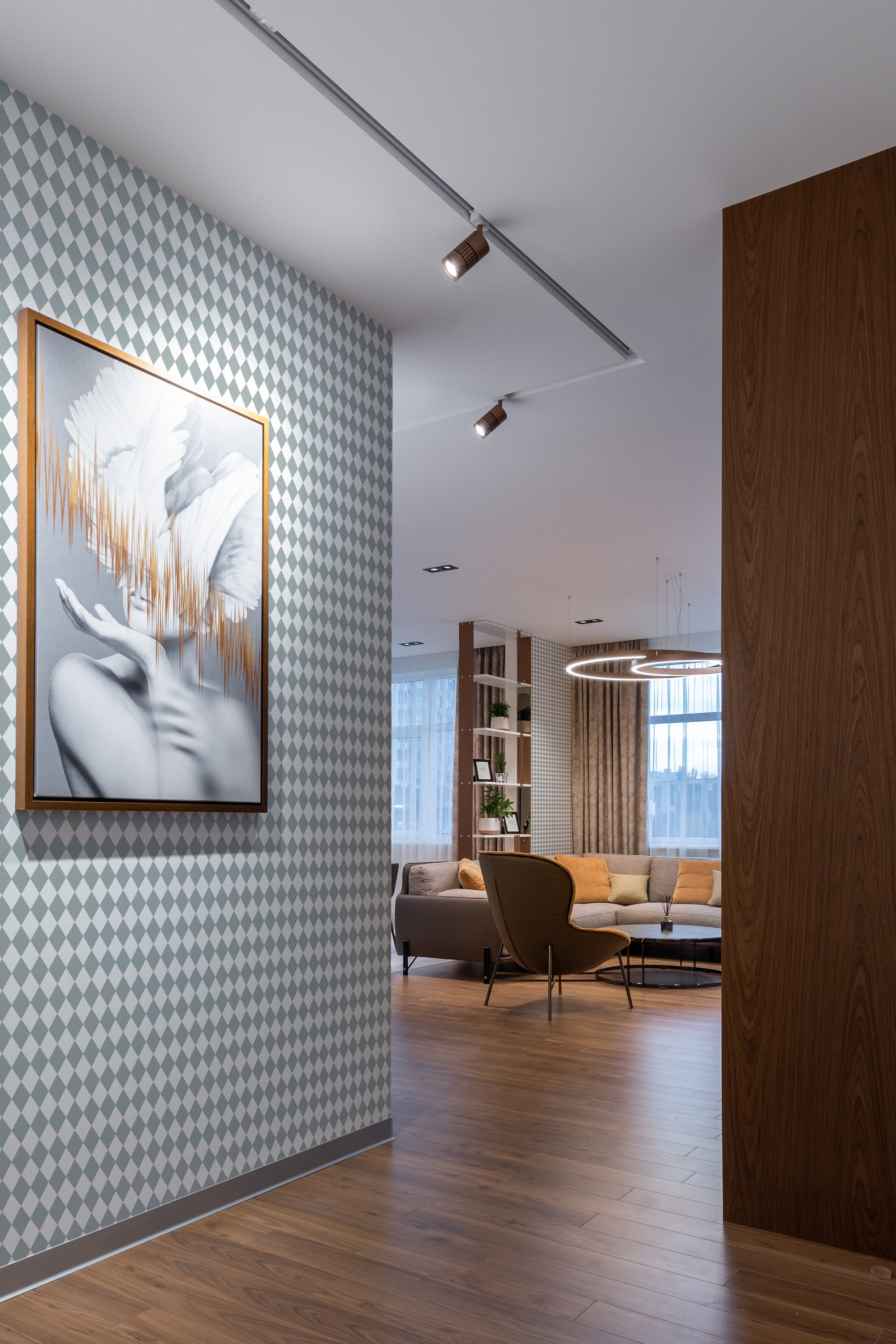 A room with light gray and white diamond-patterned wallpaper called Beachy Harlequin, complemented by wooden flooring and contemporary furniture.  Traditional wallpaper.