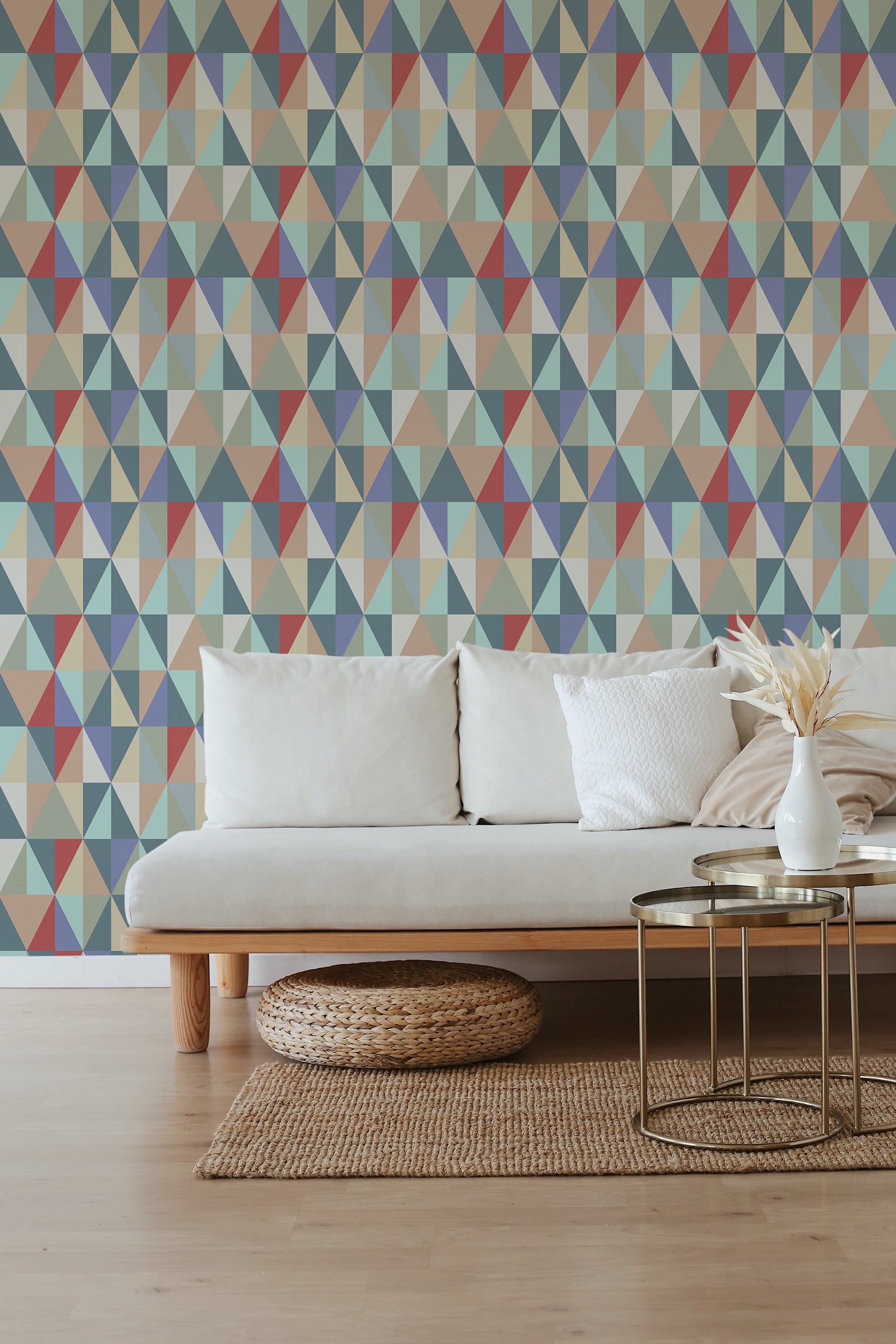 A room with a colorful geometric wallpaper design of vivid triangles in shades of blue, red, beige, and green, creating a vibrant pattern that contrasts with the neutral-toned sofa and minimalistic d��cor. Traditional wallpaper.