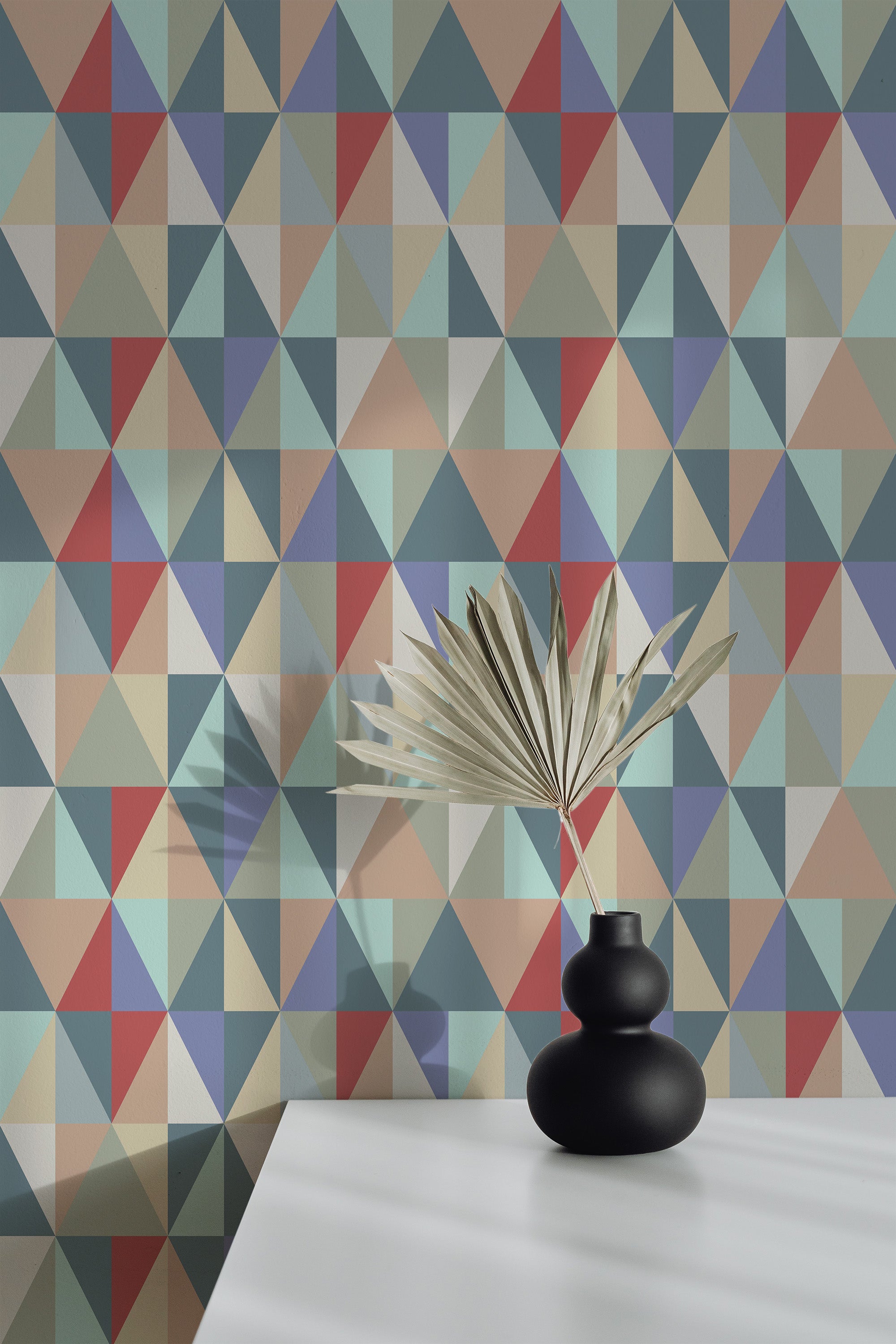 Self-adhesive wallpaper with a Vivid Triangles design, combining various muted tones including teal, red, beige, and light blue, geometric pattern creating a dynamic and modern look in the room.