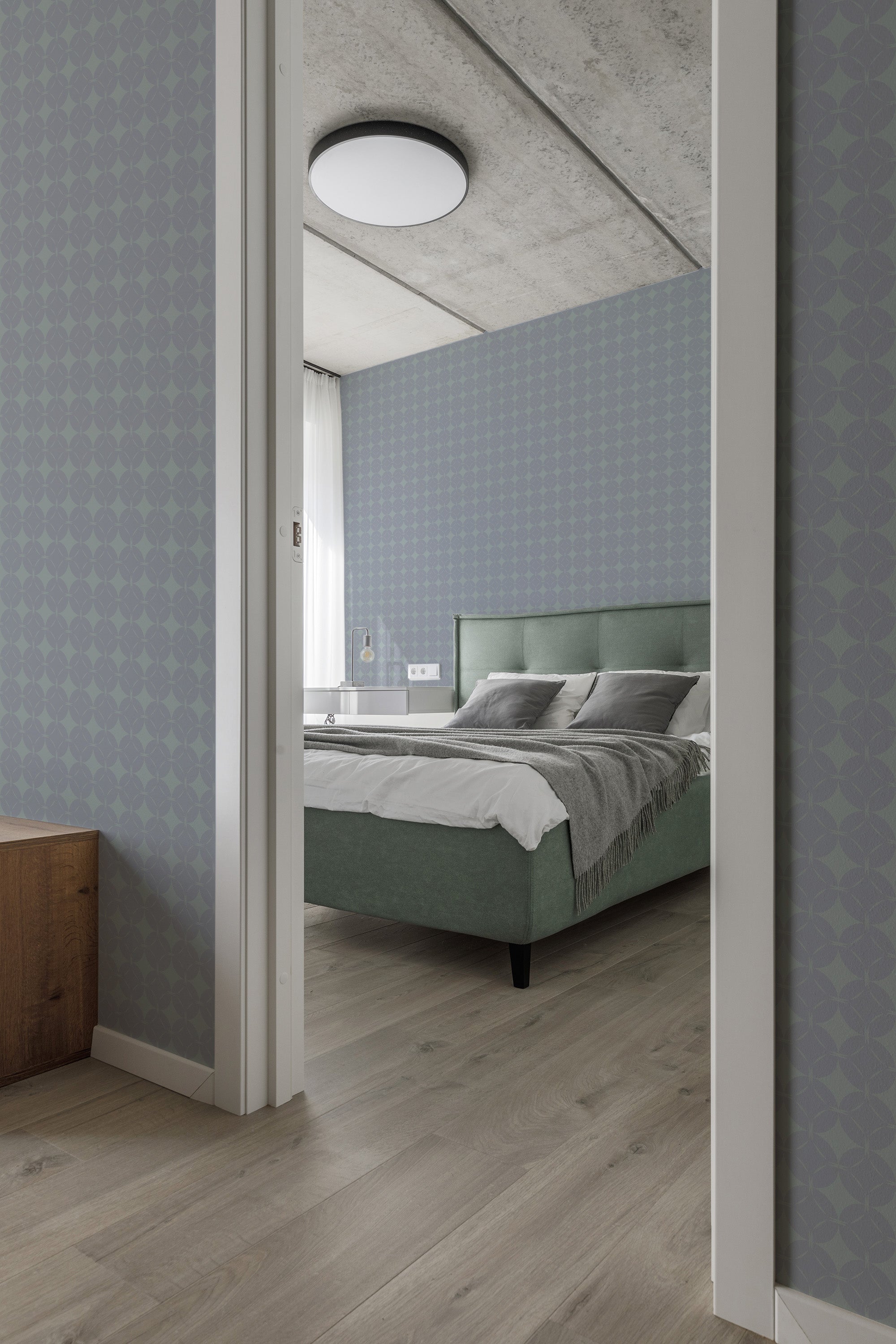 A room with muted blue wallpaper patterned with a repeating geometric diamond design, called Gemstone, that creates a subtle, elegant backdrop. Traditional wallpaper.
