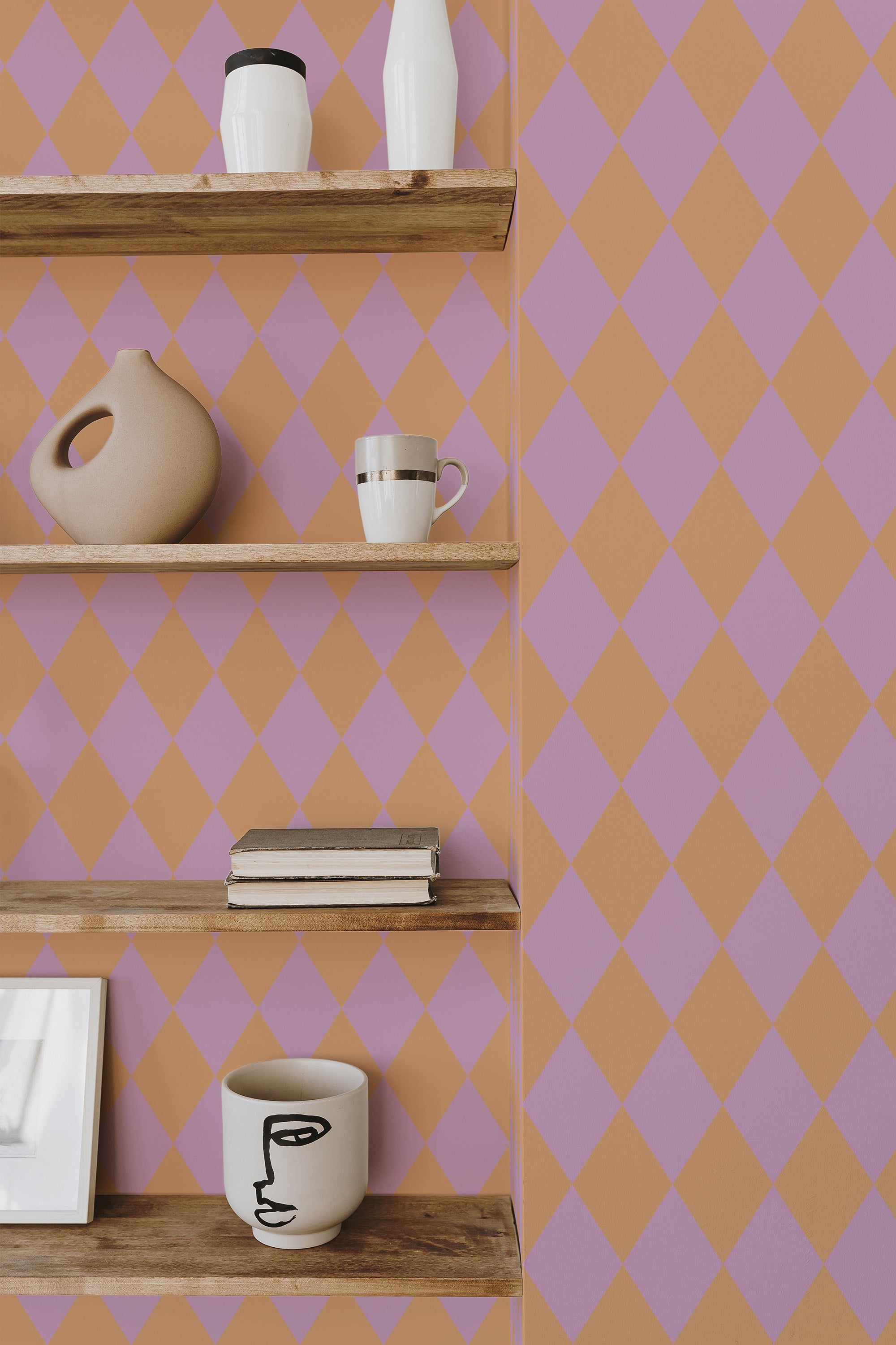 Self-adhesive wallpaper with a pink and orange harlequin diamond pattern, arranged in a diagonal grid over the length of the wall.