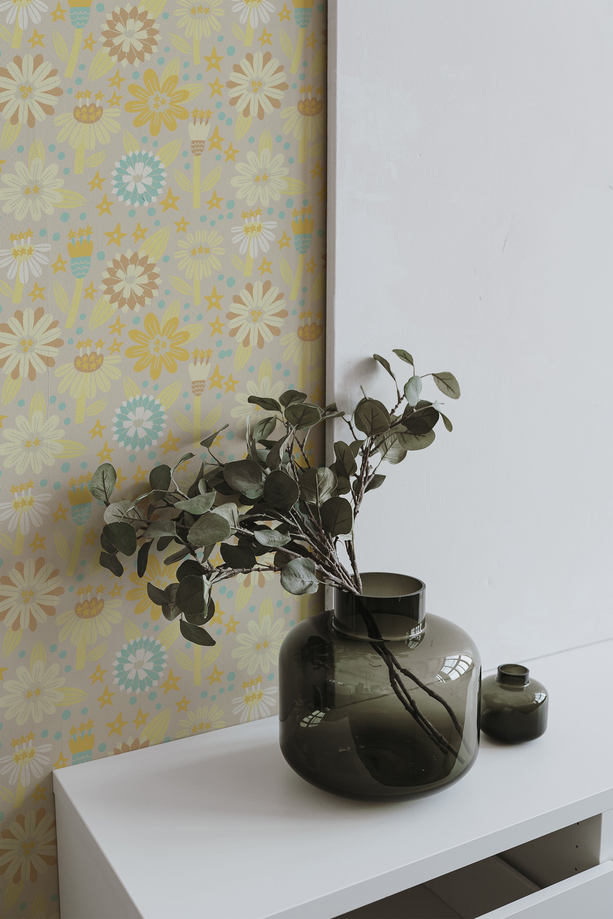 Self-adhesive wallpaper with a vintage Scandinavian design in soft pastel hues of yellow, blue, and white, forming whimsical flowers, leaves, and geometric shapes.