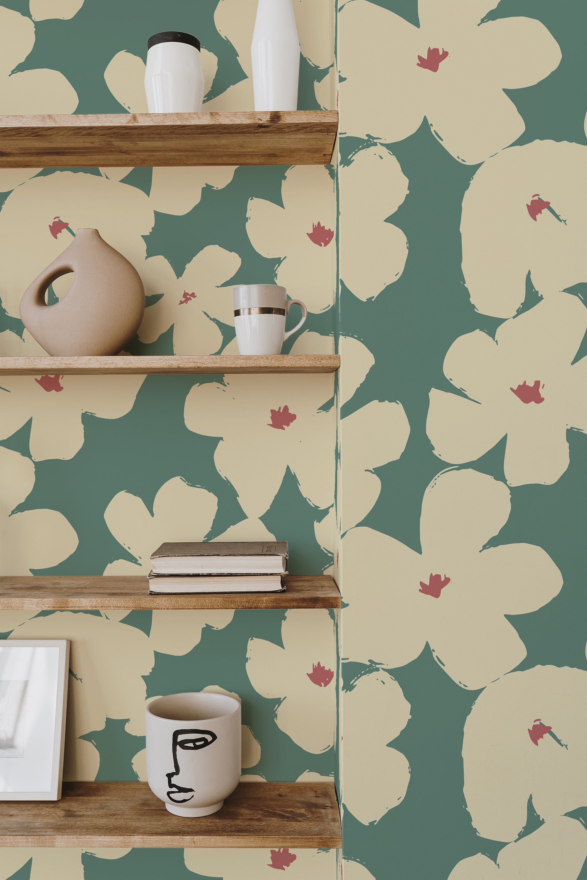 Self-adhesive wallpaper with large sage green and cream floral patterns accented by small red details, applied in a nursery setting with wooden shelves.