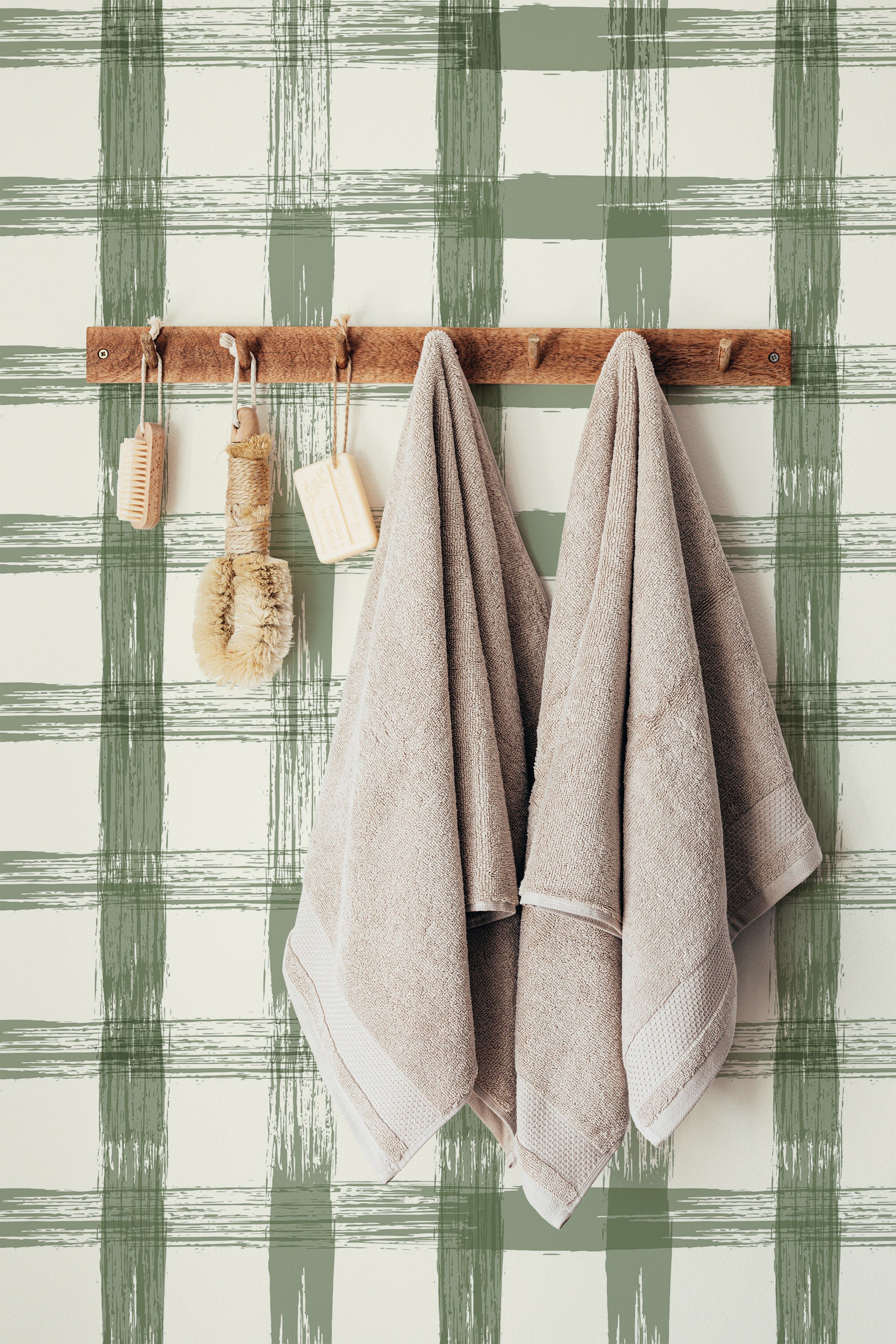 Self-adhesive Farmhouse plaid wallpaper with green and white stripes, with a wooden towel rack and beige towels against it.