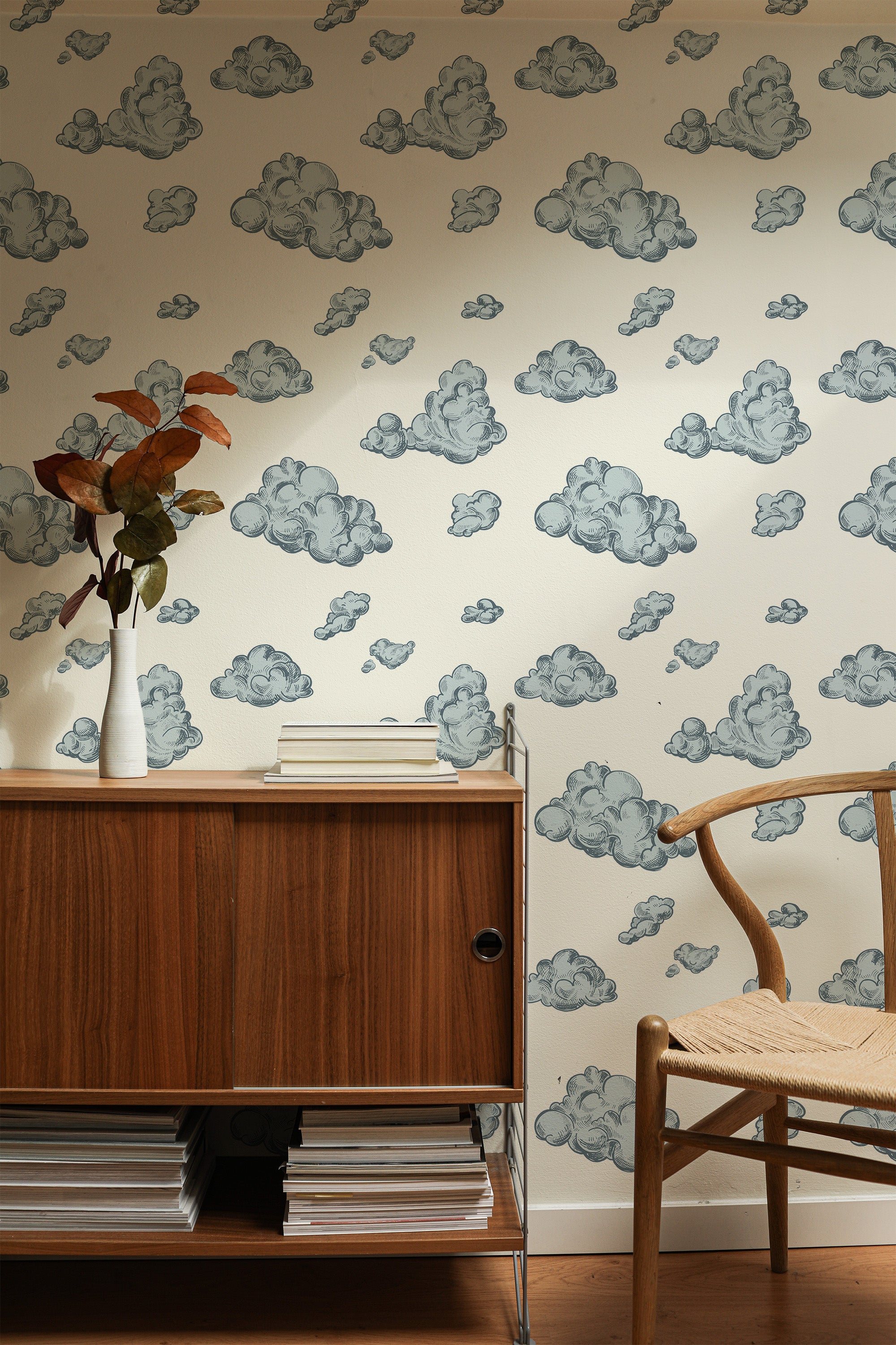Self-adhesive vintage cloud wallpaper with blue and grey cloud illustrations on an off-white background, complementing wooden furniture in the room.