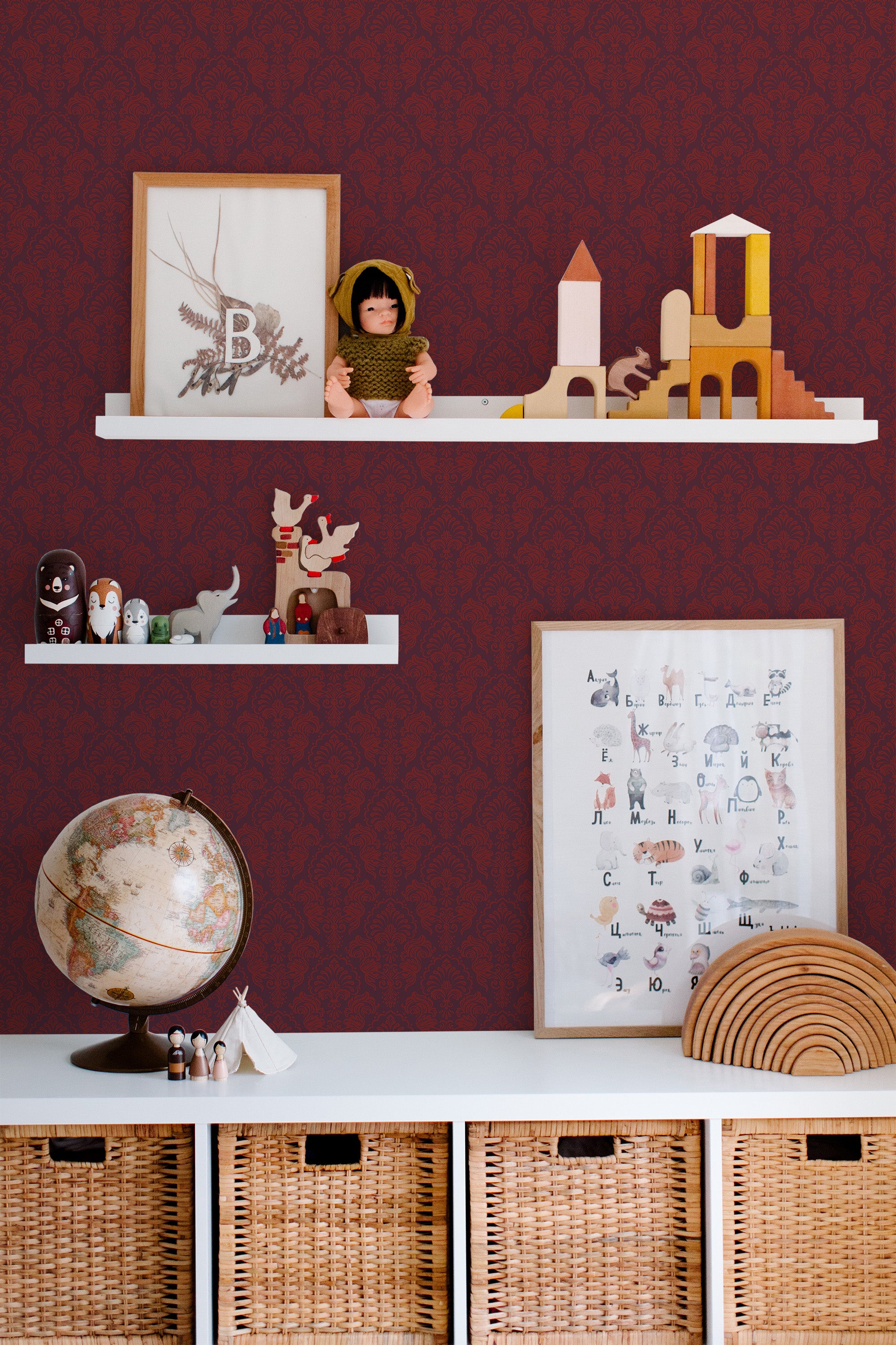 Self-adhesive Burgundy damask wallpaper with intricate patterns on a room wall, accented by shelving with toys and decor.