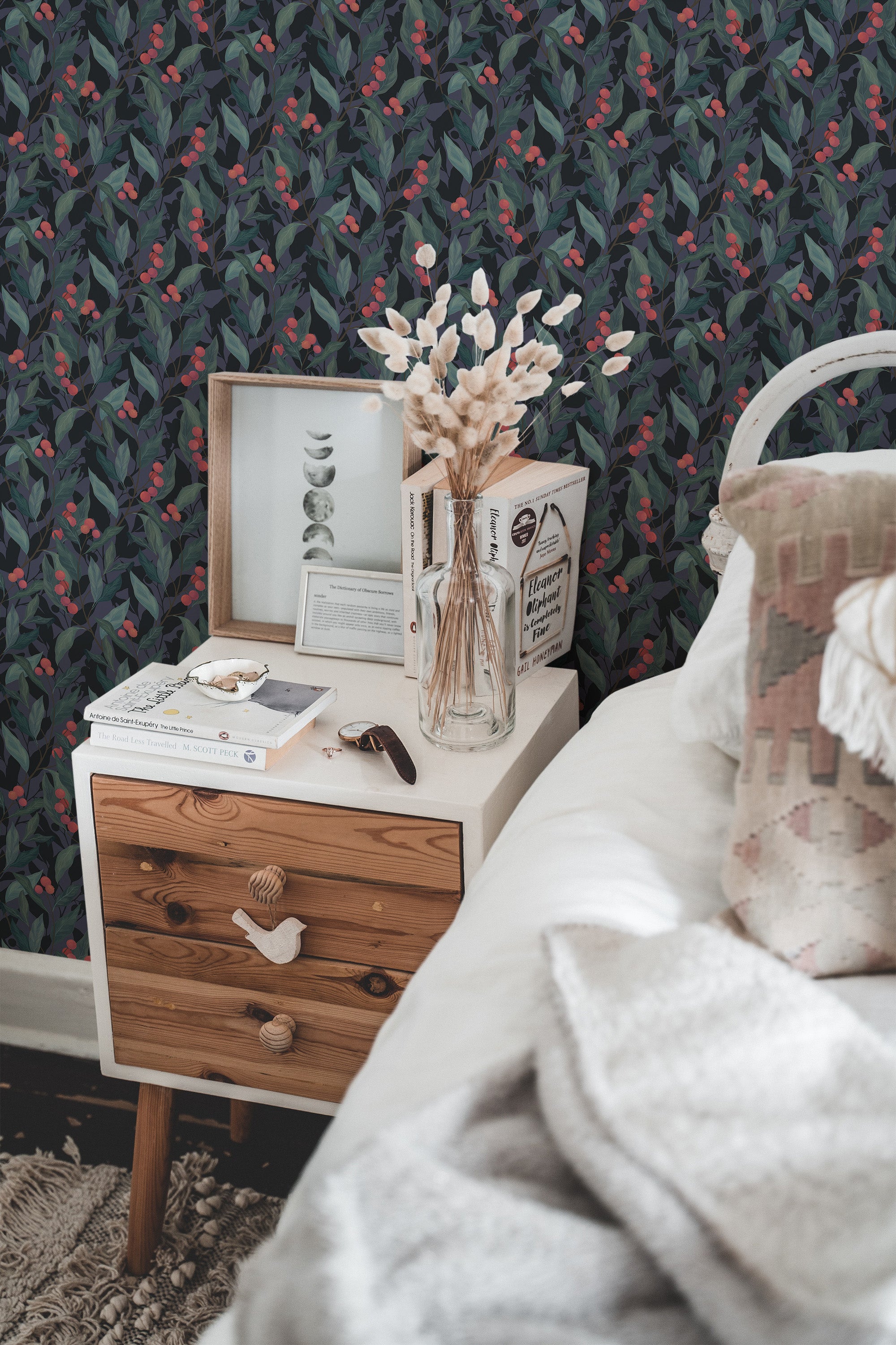 Self-adhesive wallpaper with a Night berry design, including stylized berry and leaf patterns in red and green on a dark background, in a cozy room with a bedside table and decor.