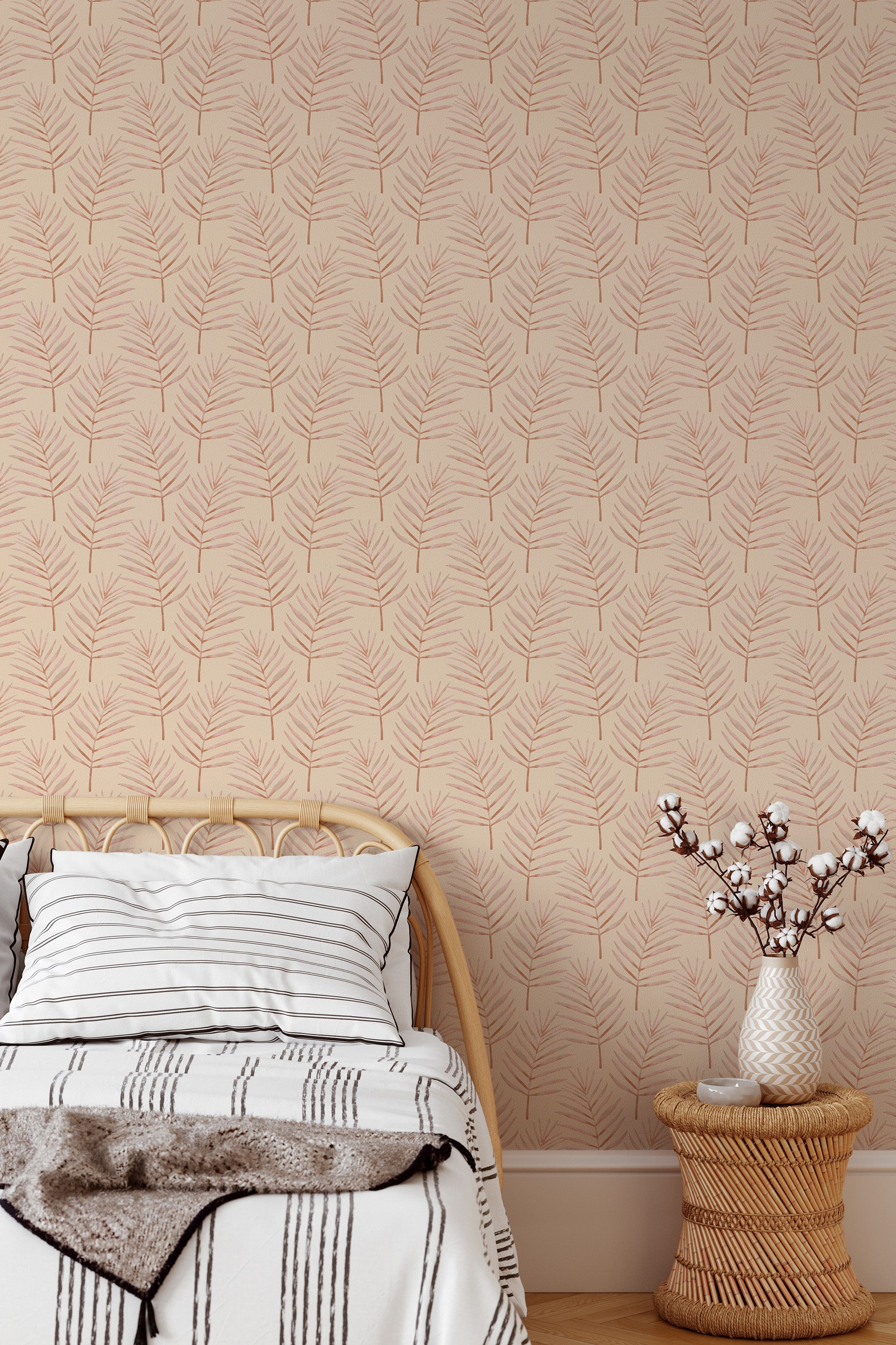 Self-adhesive Boho Palm leaf design wallpaper in subtle tones on a bedroom wall behind a bed with cozy blankets and a vase of cotton branches on a wicker basket.