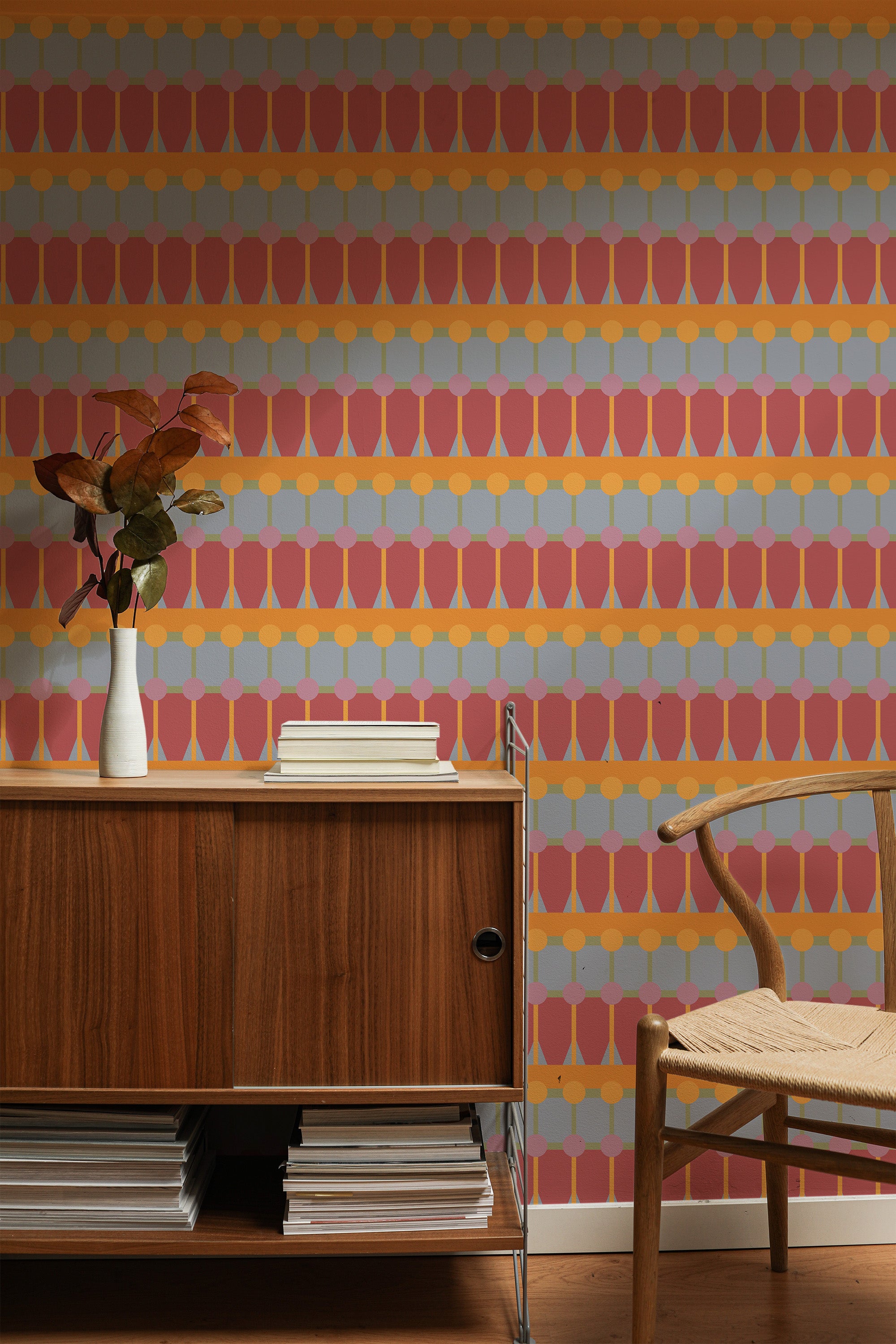 Self-adhesive Retro bold geometry wallpaper with overlapping circles in shades of orange, pink, and blue on a room wall, accompanied by wooden furniture.