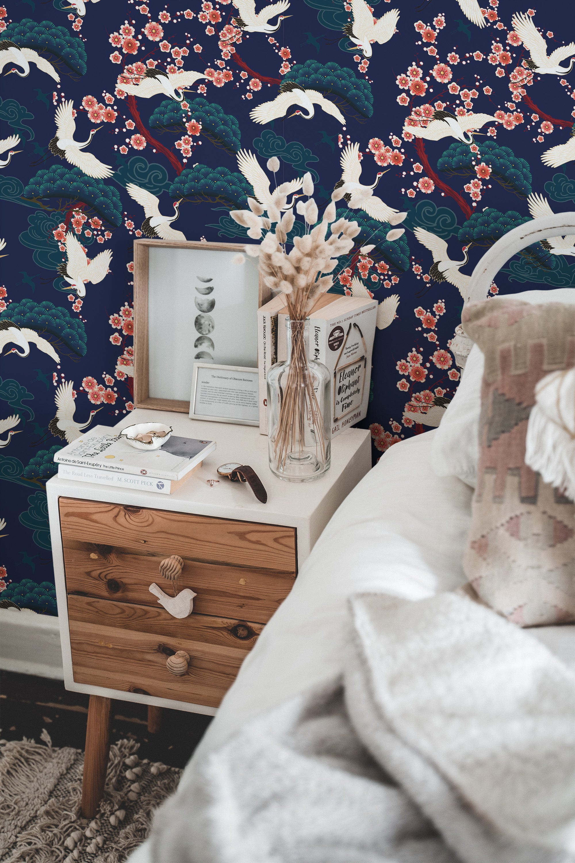 Self-adhesive wallpaper with a bold cranes pattern in blue background, accented with pink flowers and white birds in a furnished room.