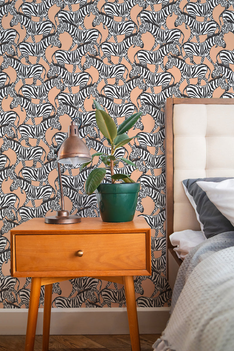 Self-adhesive Peach Zebra wallpaper with a pattern of black and white zebras on a peach background in a bedroom setting.