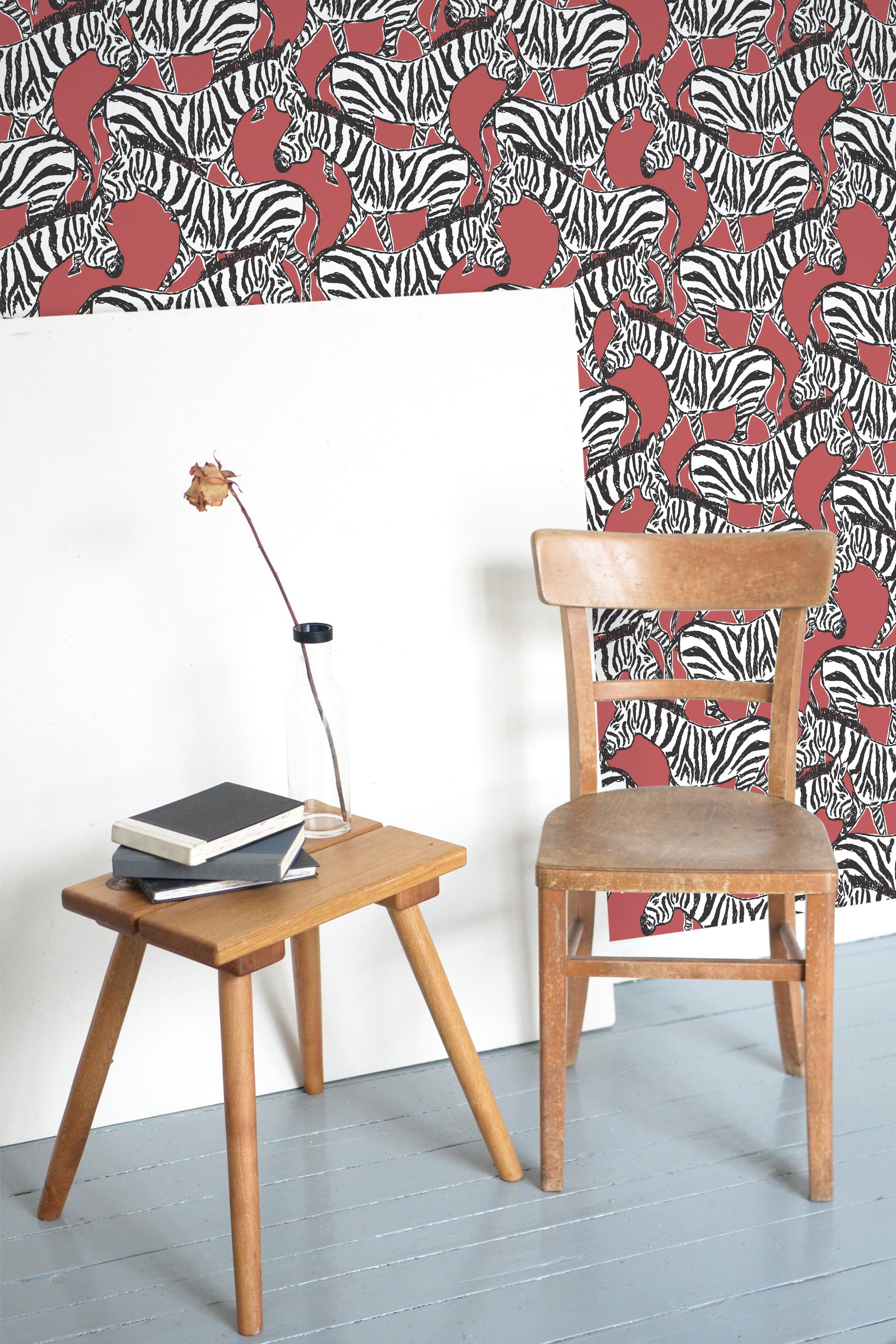 Self-adhesive Red Zebra wallpaper with a pattern of red zebra stripes on a white background, in a room with a wooden chair and table.