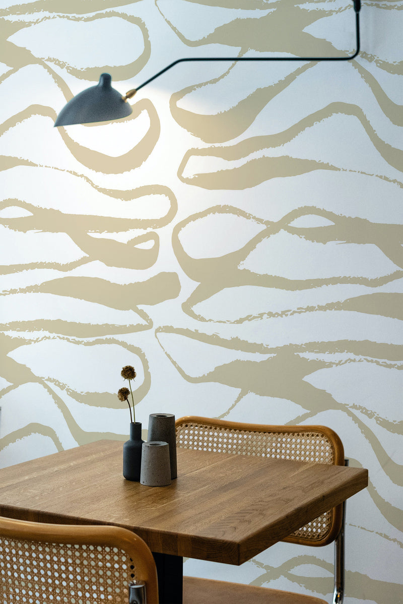 Self-adhesive wallpaper with abstract honey-colored line patterns on a light background, above a wooden table and chair.