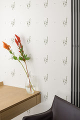 Self-adhesive wallpaper with a repeated pattern of serious cat faces on a plain background, accenting a modern room with minimalist furniture.