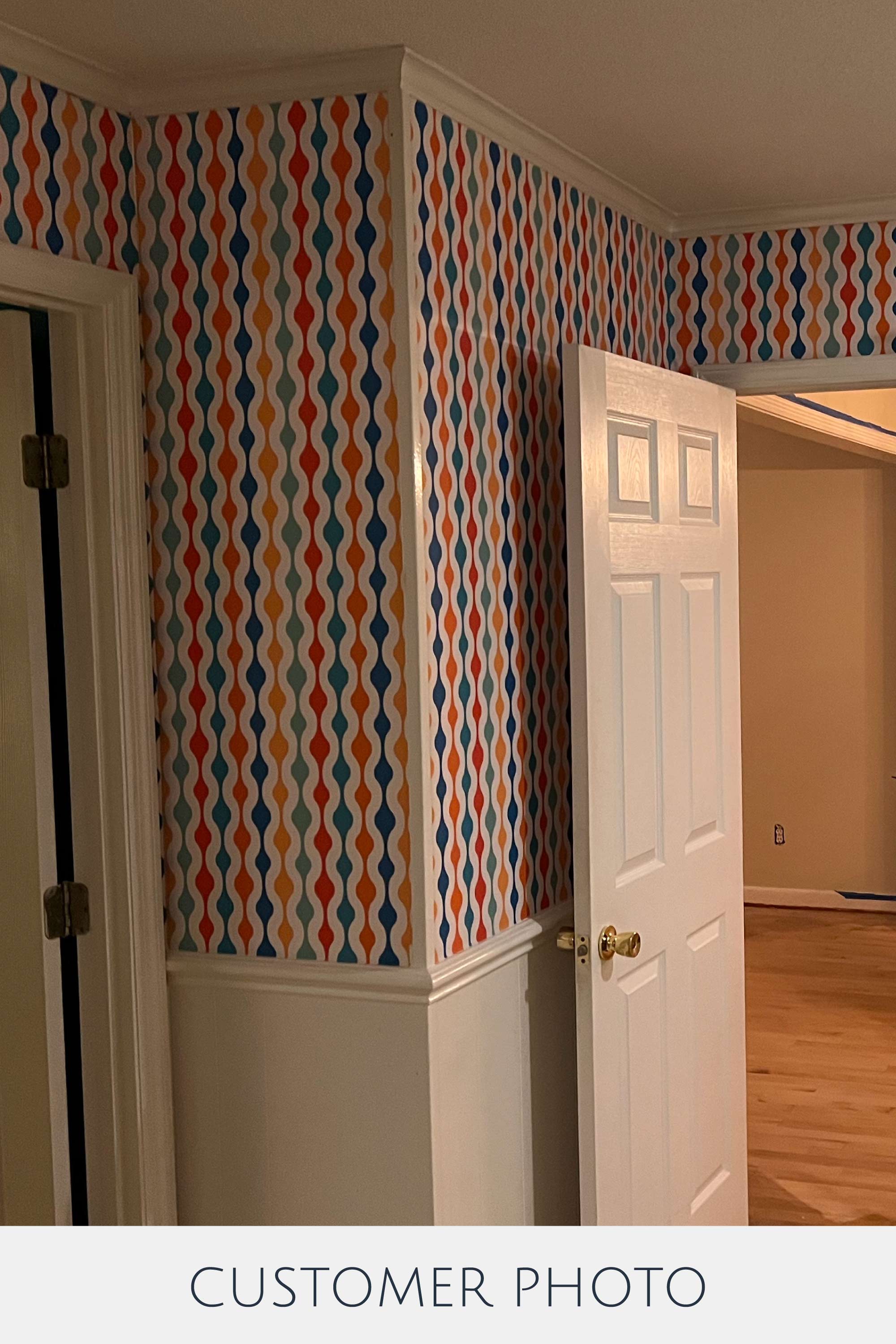 Colorful retro wallpaper with wavy vertical patterns in vibrant shades of orange, blue, and yellow, creating a dynamic and lively atmosphere in the room. Traditional wallpaper.