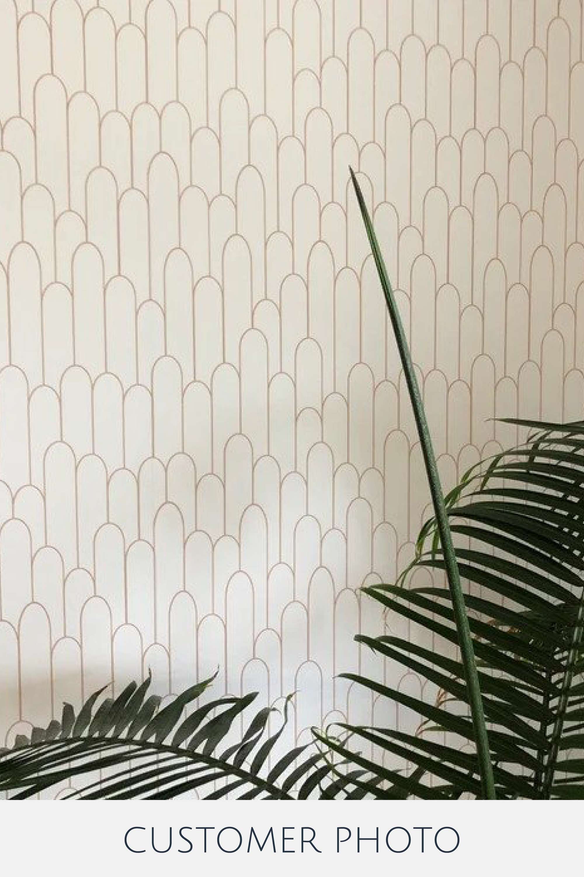 An art deco-style pattern with repetitive, arched shapes resembling a fence in a soft, muted tone. Traditional wallpaper.