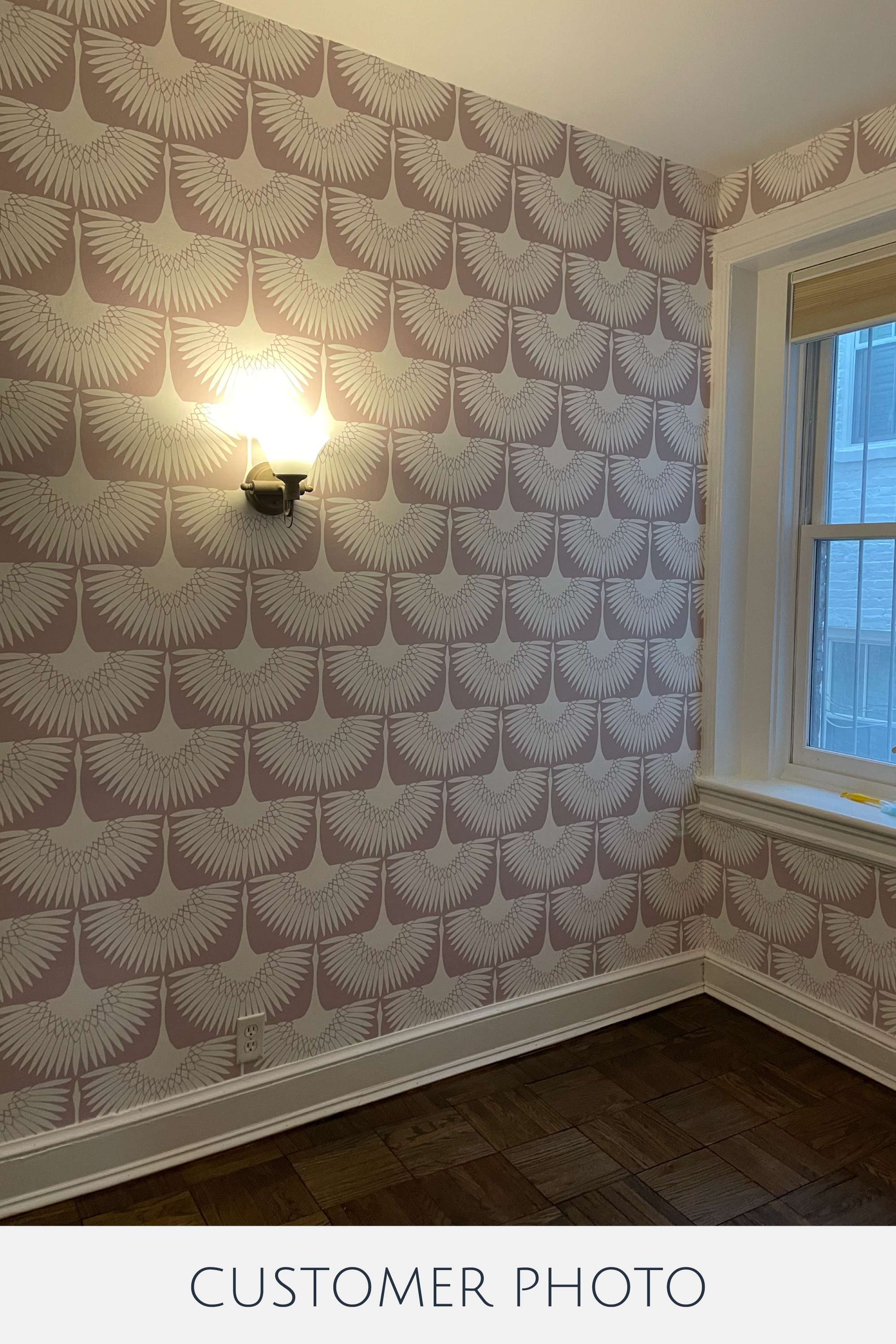 An image of a room with soft pink wallpaper adorned with a repetitive pattern of elegant white swan-like shapes, creating a soothing and symmetrical design. Traditional wallpaper.